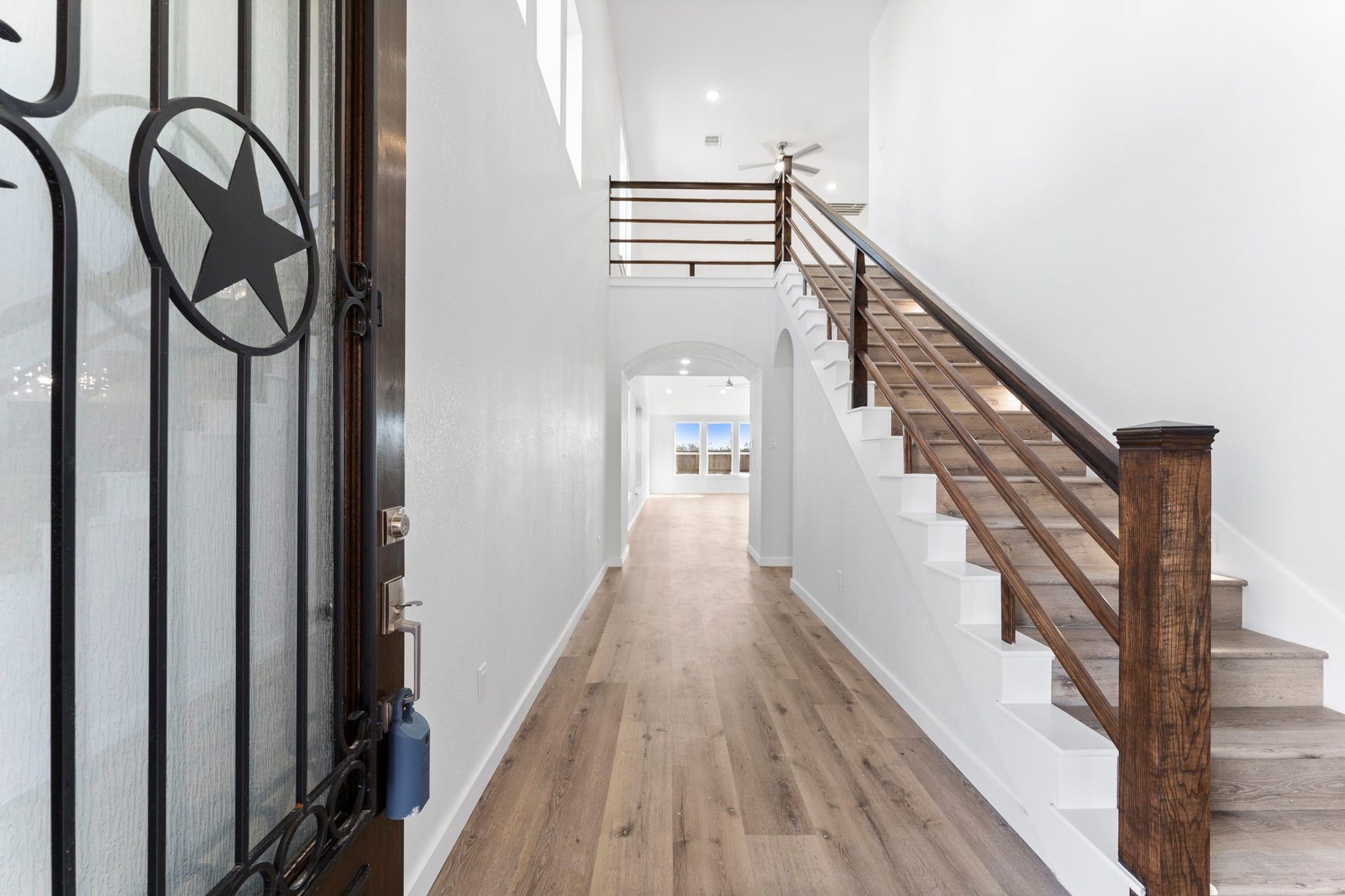 2230 Fresh Flower Way, Richmond, TX 77406 As you enter, youre greeted by soaring ceilings and a sweeping view of the open-concept layout. Beautiful upgraded flooring leads the way, complemented by a striking staircase with modern dark wood railings.