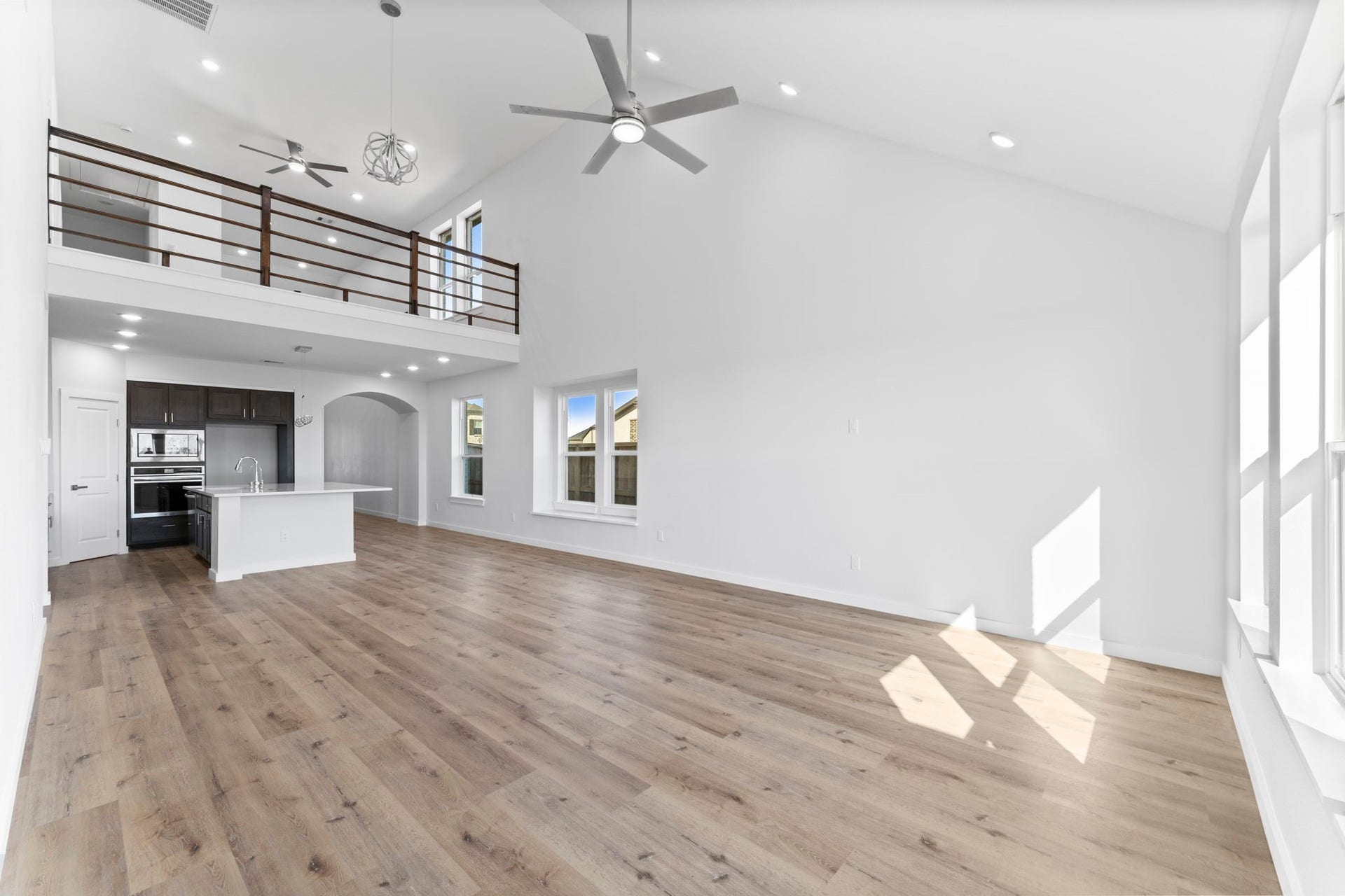 2230 Fresh Flower Way, Richmond, TX 77406 From this perspective, the home's unique layout shines, featuring a dramatic loft-style overlook with dark wood railings and elegant arched transitions.