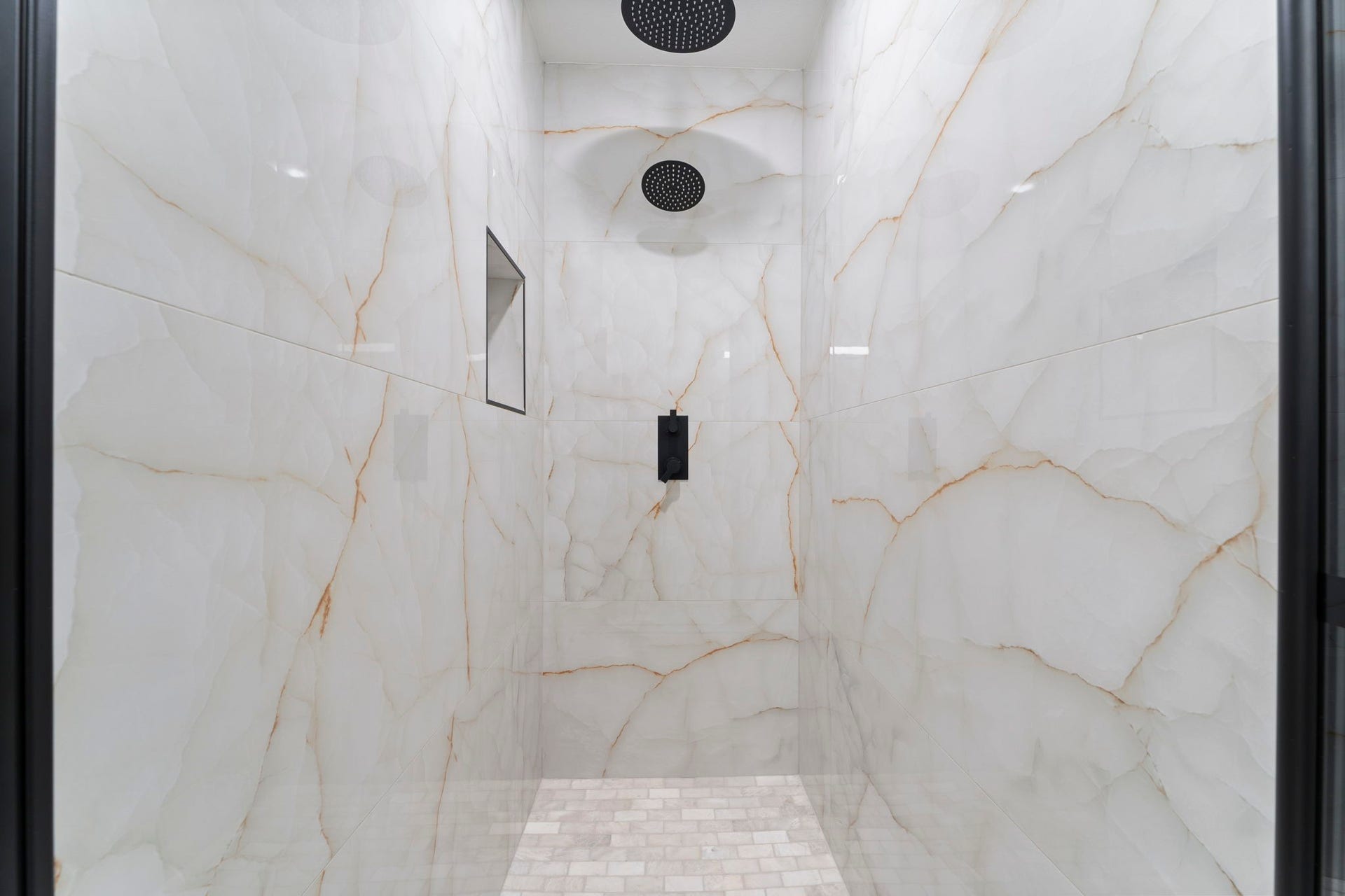 2230 Fresh Flower Way, Richmond, TX 77406 Spa Day, Every Day. Step into luxury with this walk-in shower featuring stunning large-format marble-look tiles and a high-end matte black rainfall showerhead.