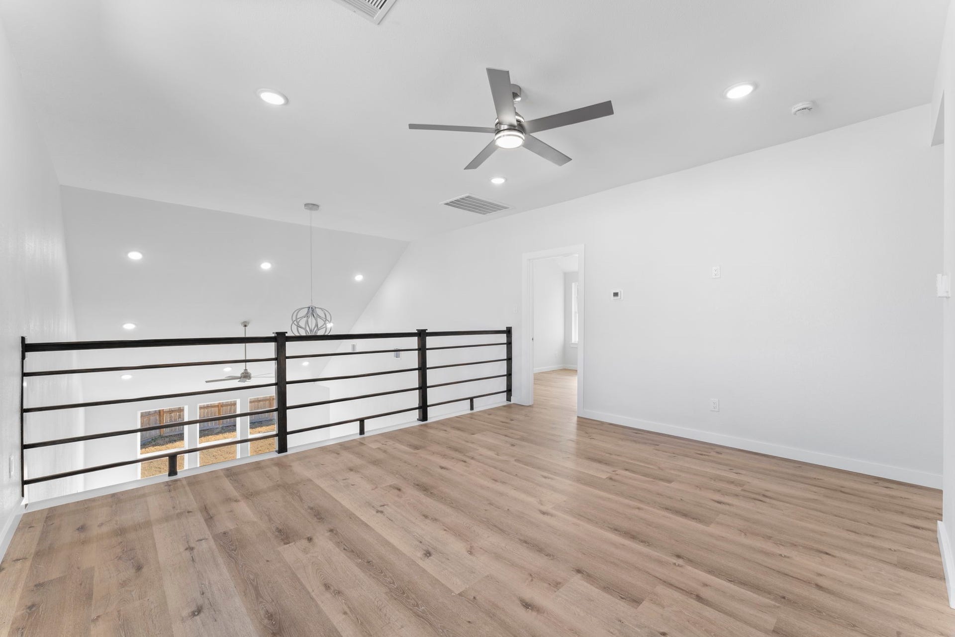 2230 Fresh Flower Way, Richmond, TX 77406 Stylish dark wood horizontal railings frame the loft, maintaining a connected feel while providing a distinct upstairs retreat.