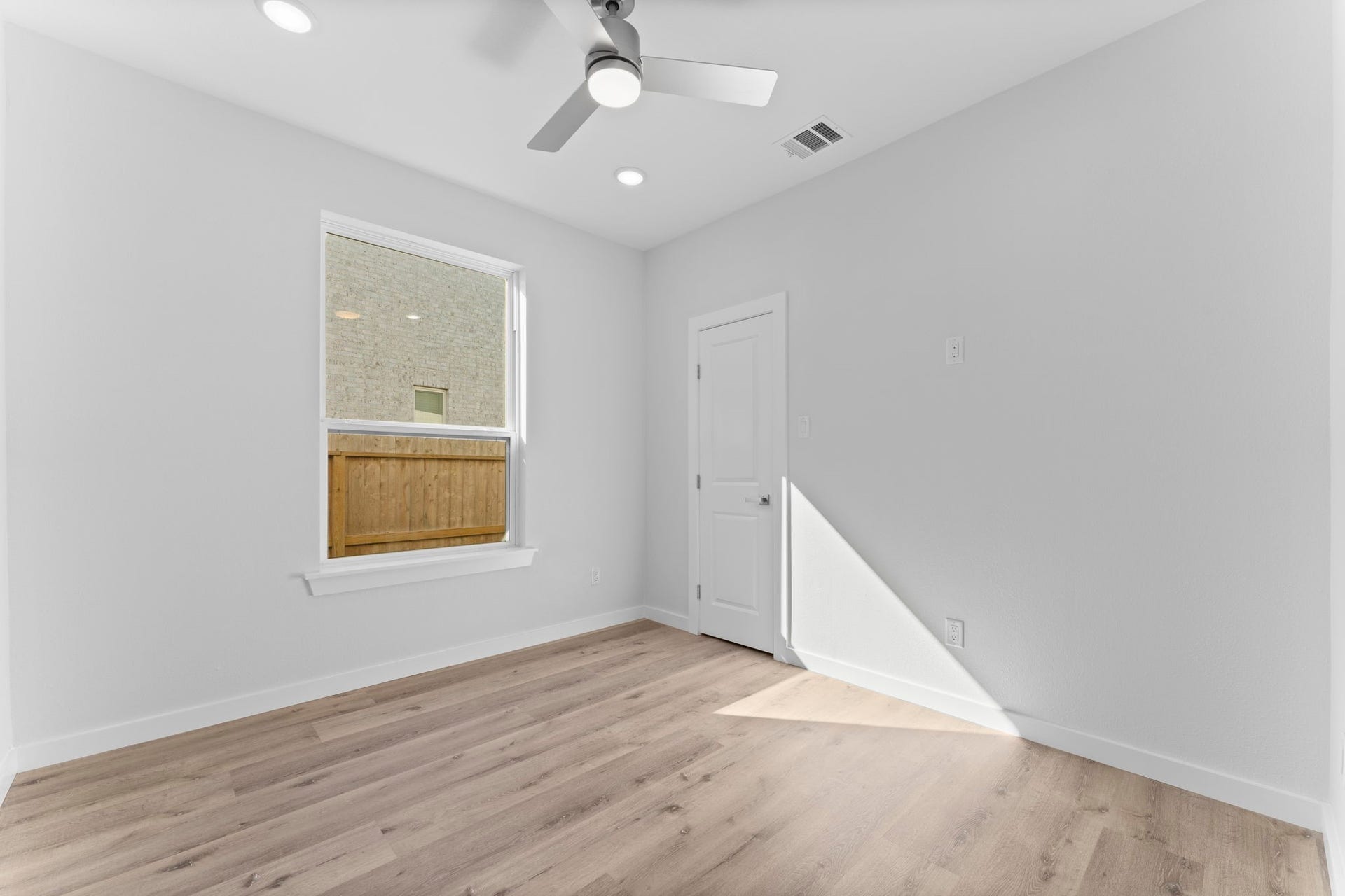 2230 Fresh Flower Way, Richmond, TX 77406 This spacious secondary bedroom downstairs offers a minimalist sanctuary with plush natural light pouring in from the oversized window. Equipped with a modern ceiling fan and neutral tones, its a blank canvas ready for your personal touch.