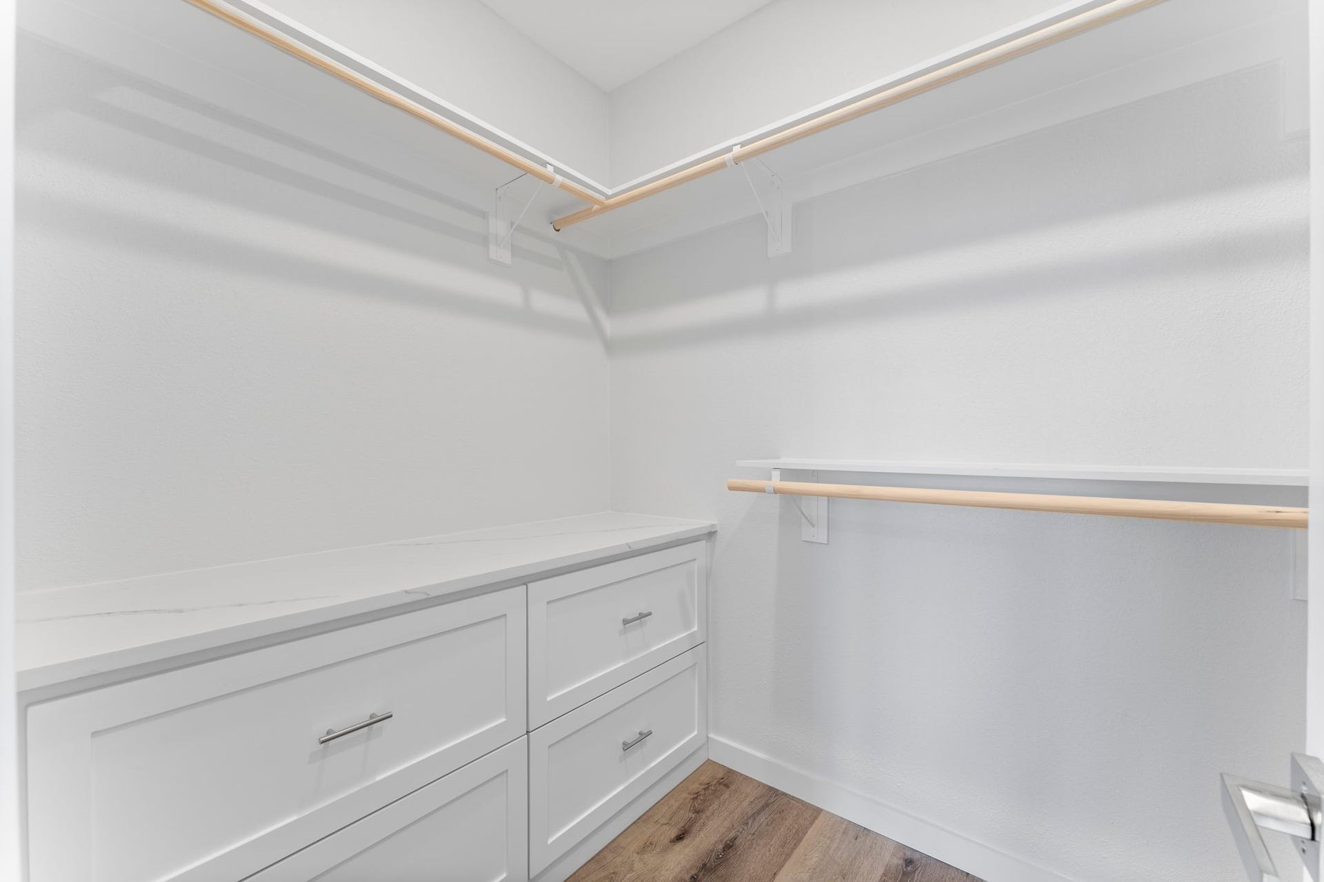 2230 Fresh Flower Way, Richmond, TX 77406 The walk-in closet is a dream for organization, featuring built-in dresser drawers with a quartz-topped landing and multiple tiers of hanging rods to maximize every inch of space.