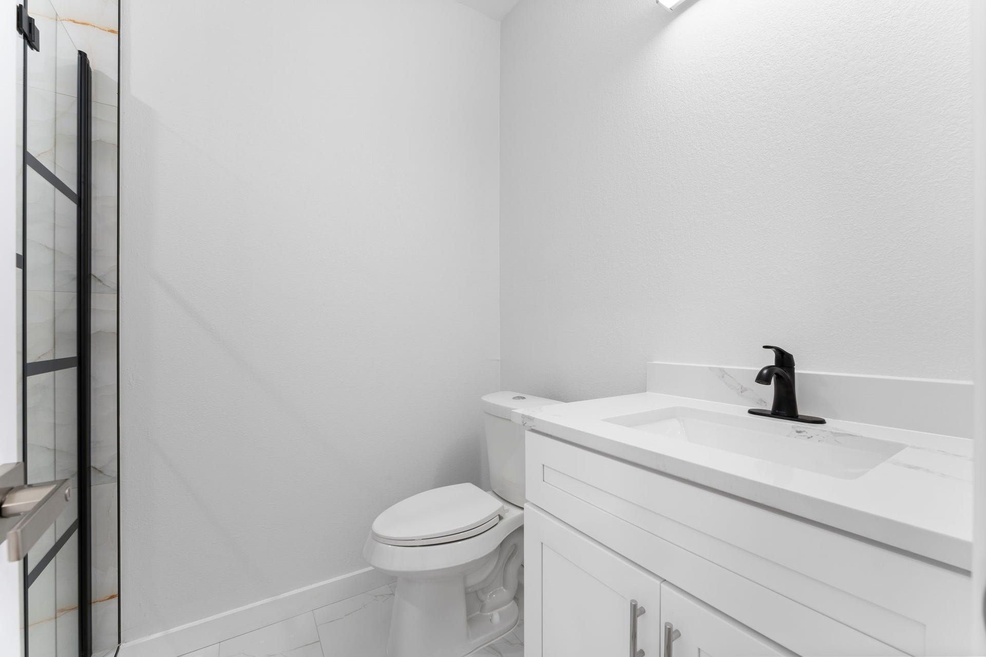 2230 Fresh Flower Way, Richmond, TX 77406 Even this downstairs secondary-bath makes a statement with a bright white vanity, quartz top, and modern matte black hardware that mirrors the home's high-end aesthetic.