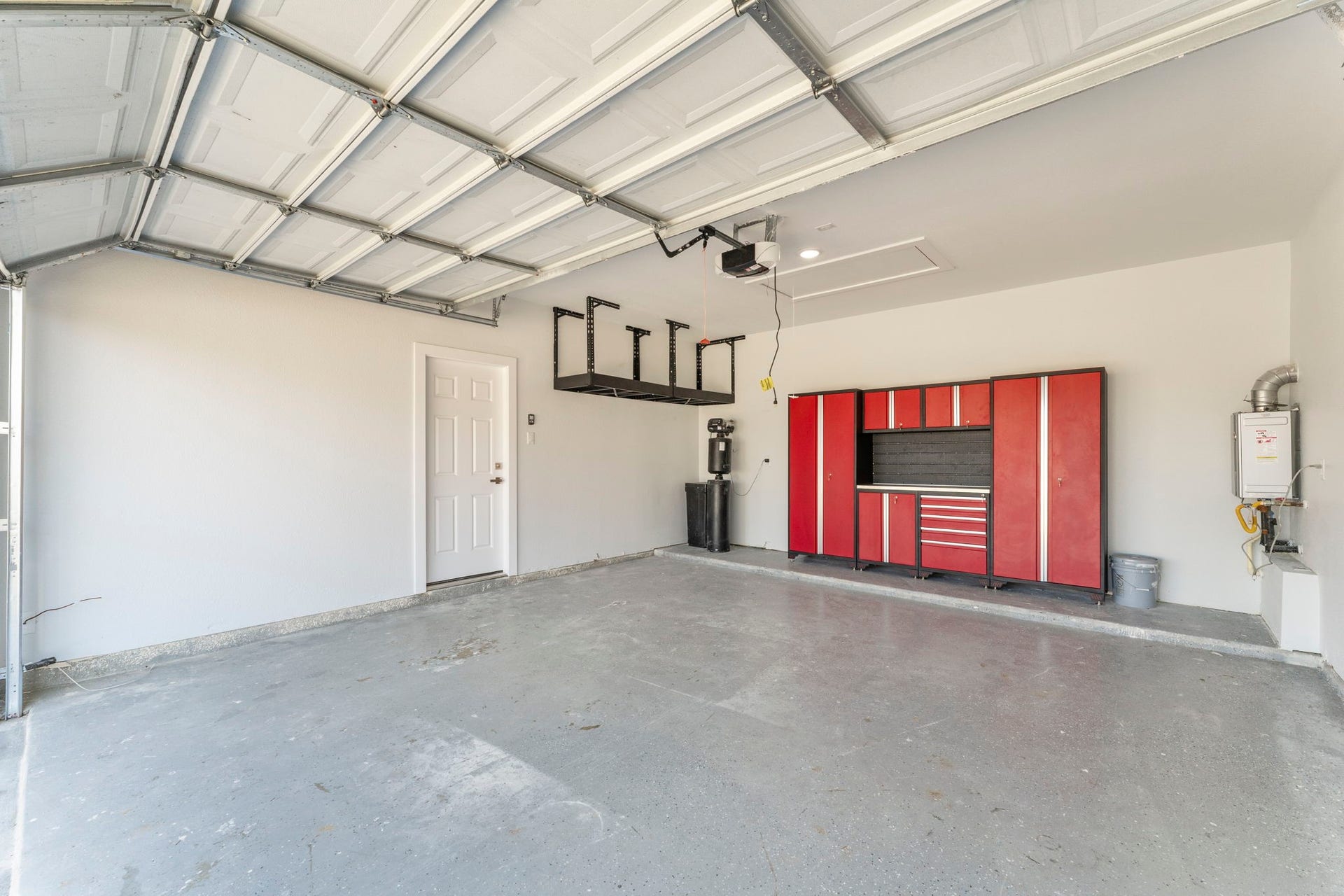 2230 Fresh Flower Way, Richmond, TX 77406 Oversized garage equipped with a professional-grade red cabinetry workstation, overhead storage racks, and a tankless water heater for efficiency.