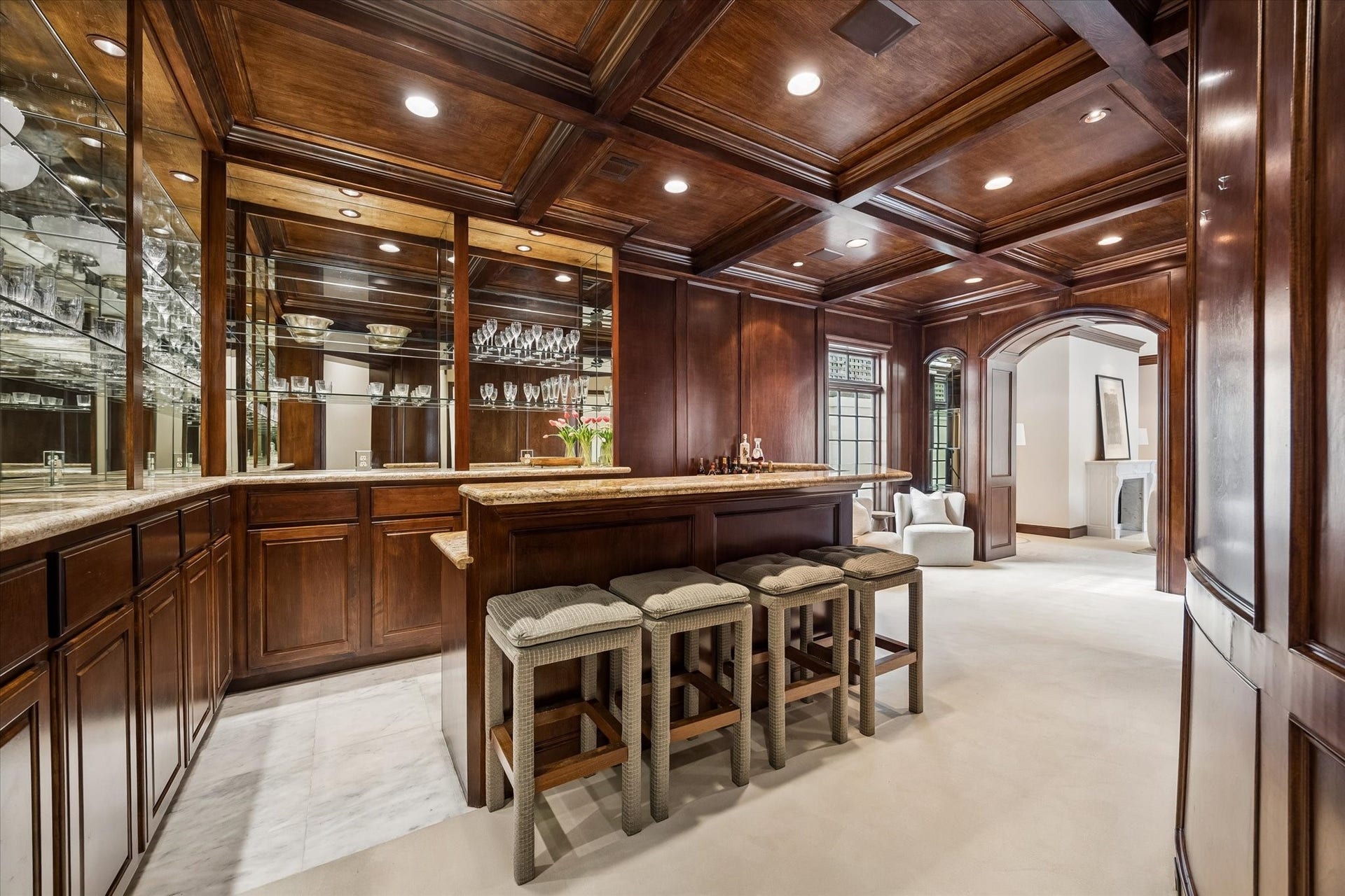 22 Eaton Square, Houston, TX 77027 Discrete speakeasy style bar with wood paneling, generous seating for 8, copper inlay sink, and glass and mirrored lit shelving.