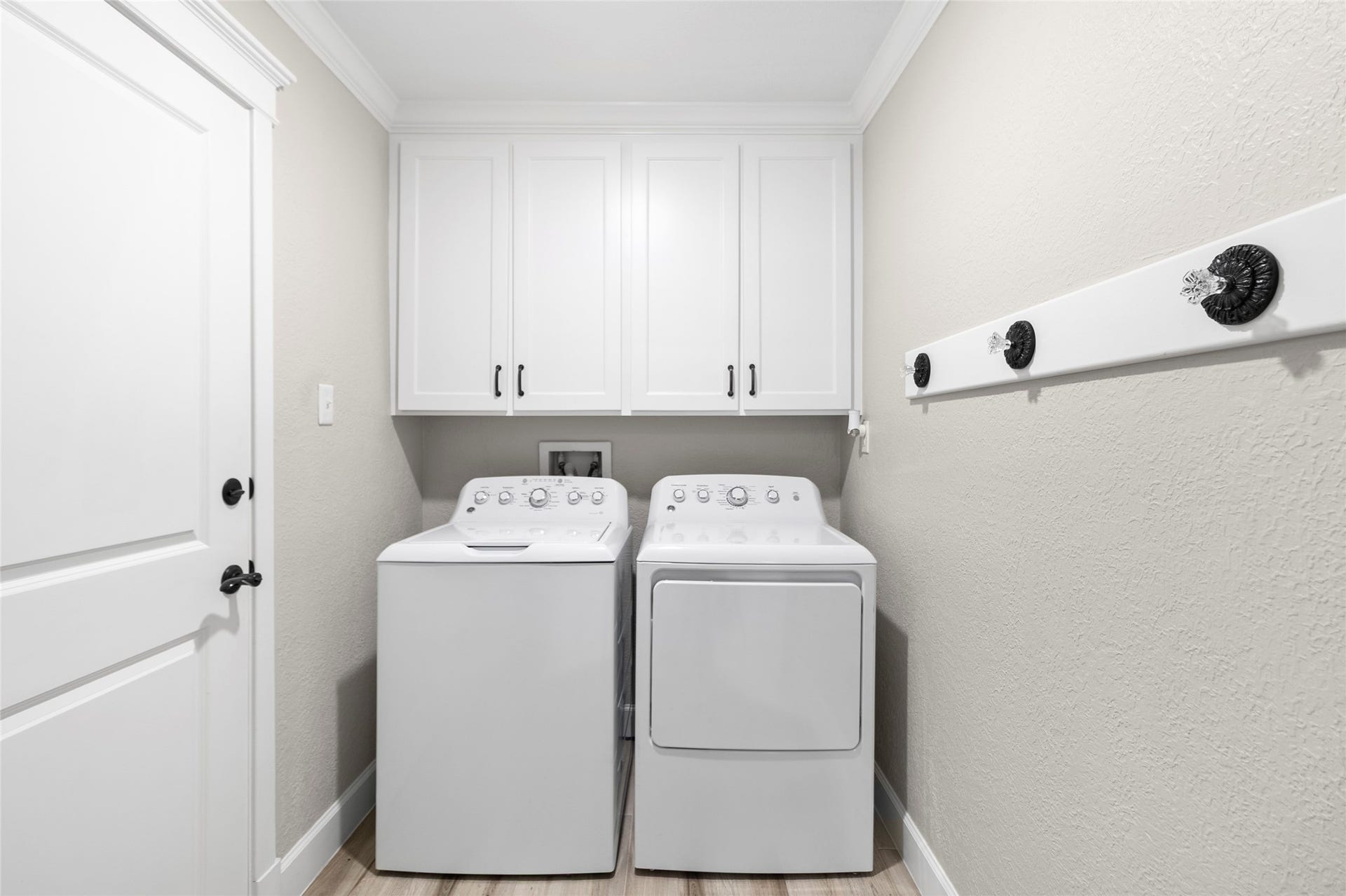 Laundry day feels effortless in your dedicated utility room featuring upper cabinetry for added storage and an organized, streamlined layout.