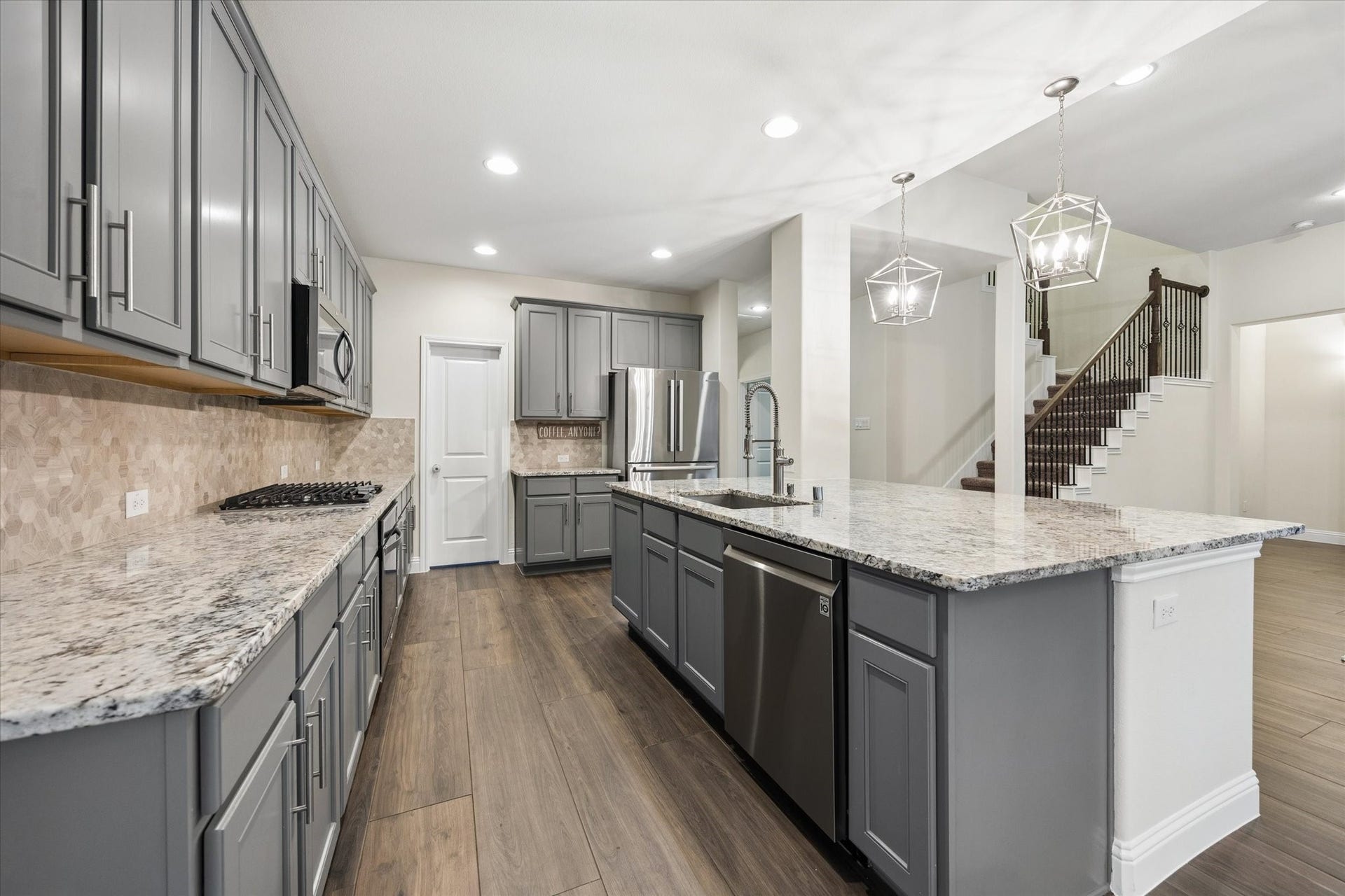 20338 Sienna Bluff Drive, Cypress, TX 77433 Stunning kitchen that features extensive gray cabinetry, granite countertops, stainless steel appliances, and a large center island with an undermount sink and seating area.