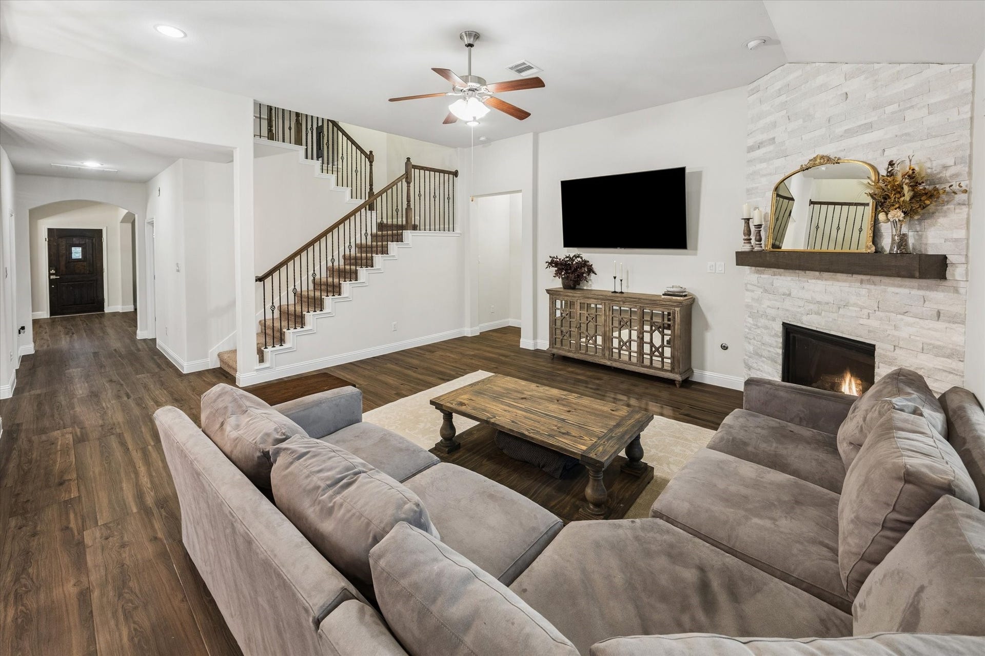 20338 Sienna Bluff Drive, Cypress, TX 77433 Fantastic living room featuring a striking stone fireplace with a wood mantel, elegant built-in-style furnishings, and a large seating area perfect for gatherings.