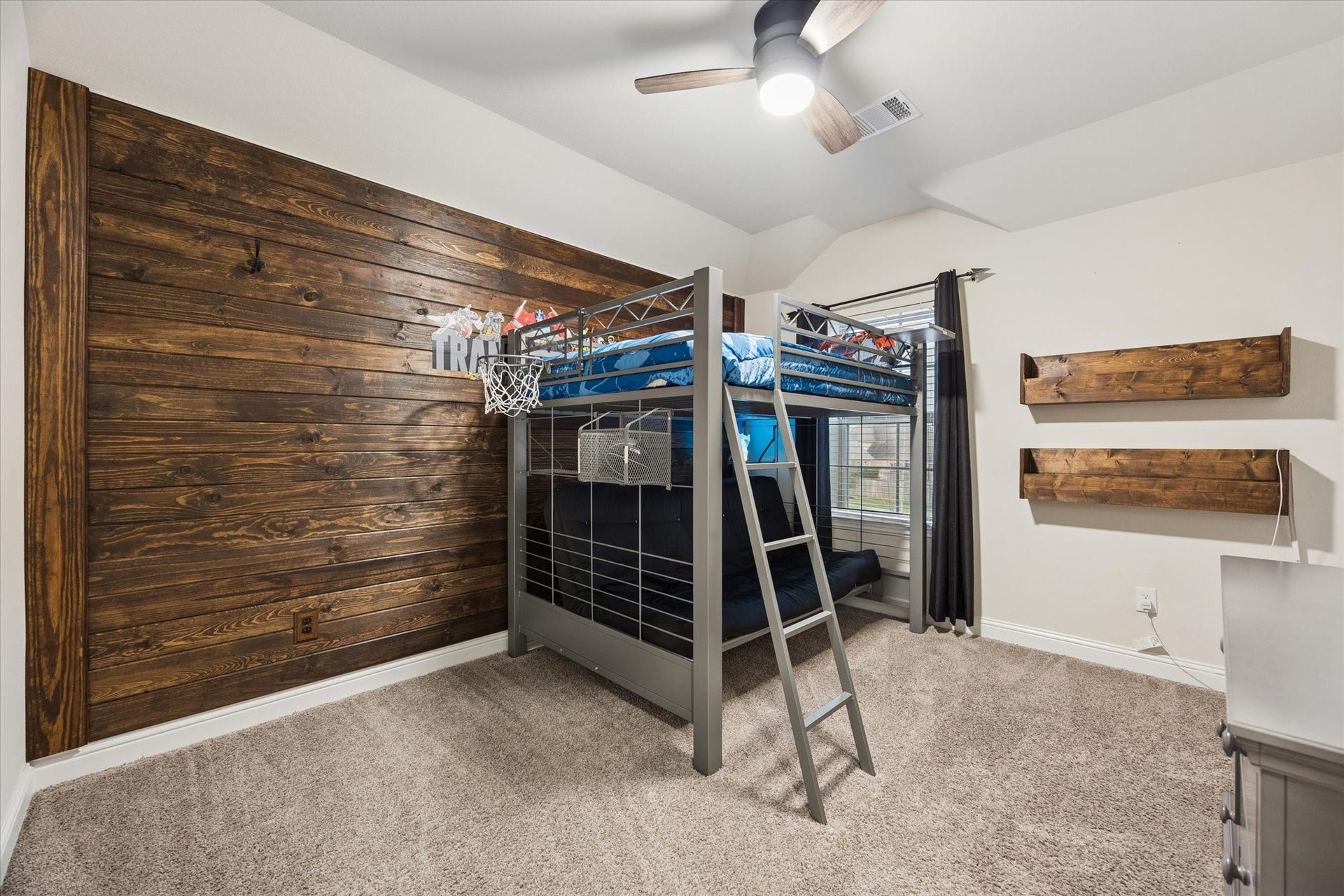 20338 Sienna Bluff Drive, Cypress, TX 77433 This inviting bedroom offers a warm and playful retreat, featuring a striking custom wood accent wall that adds rustic character and visual appeal.