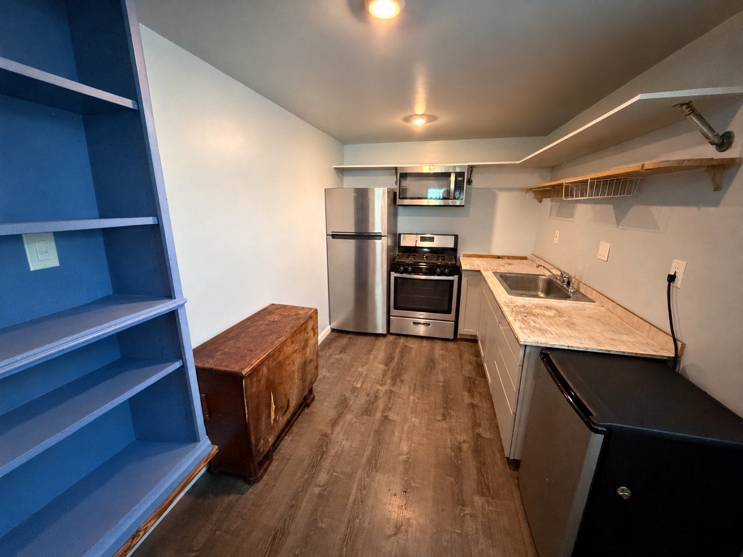 Kitchen featuring stainless steel appliances, gas range, open shelving, and countertop space.