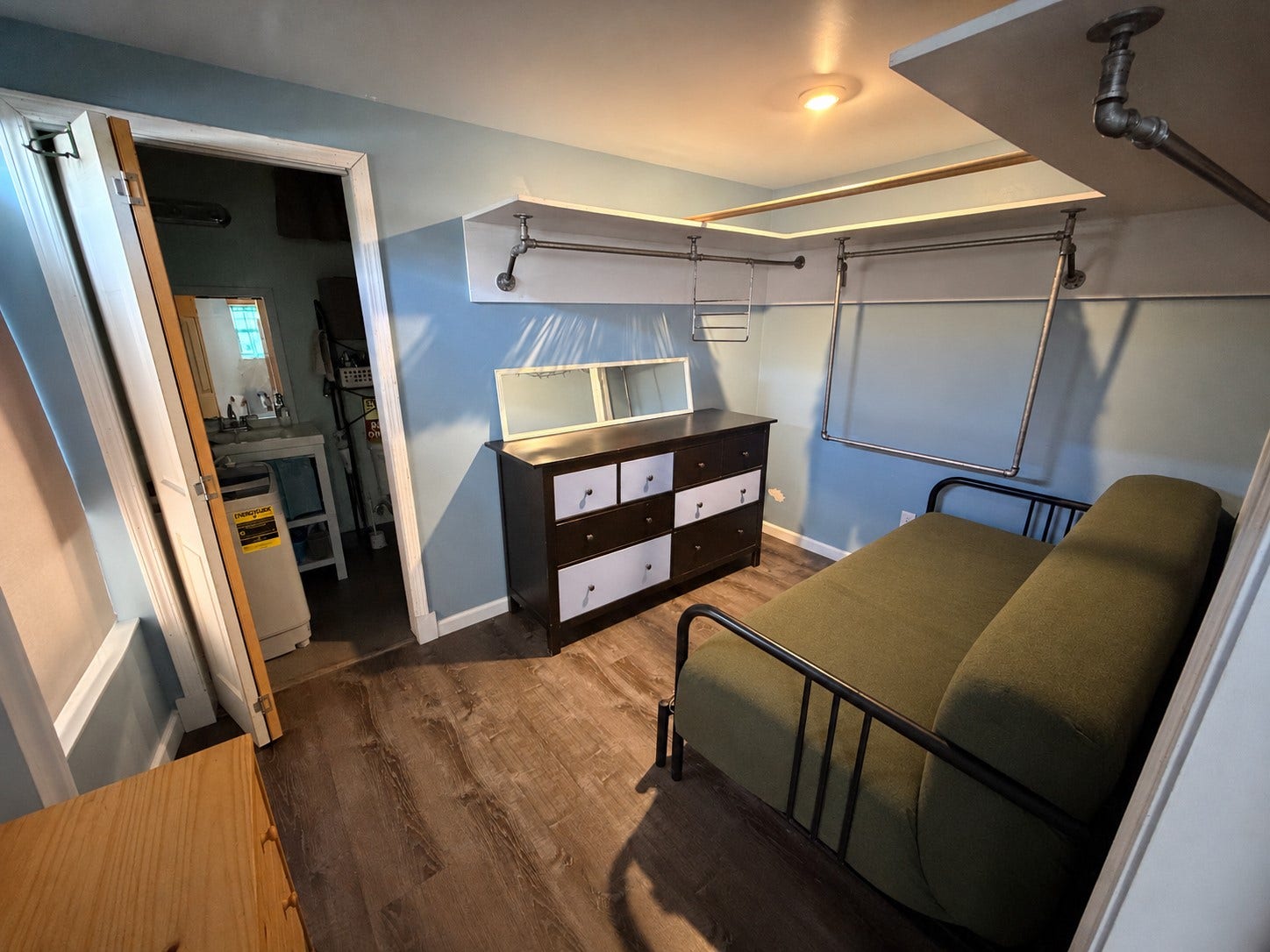 Bedroom with wood-look flooring, open closet storage, and access to the bathroom.