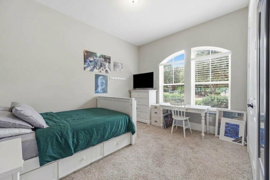 5414 Lake Hill Farm Way, Fulshear, TX 77441 Bedroom featuring light neutral paint, carpet flooring, crown molding, a central ceiling light fixture, and two arched accent windows with interior white blinds. Includes a wide reach-in closet with double white doors.
