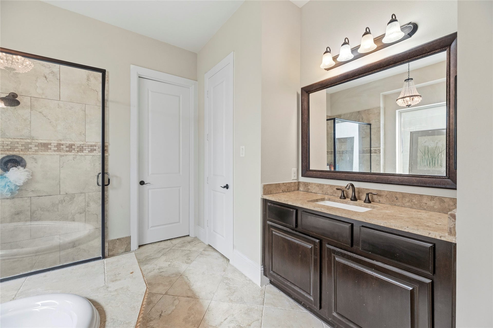 5414 Lake Hill Farm Way, Fulshear, TX 77441 Angle of the primary ensuite bathroom featuring the corner tile step-in shower with dark trim glass walls, a private water closet/linen door, diagonal tile floor, and extended dark wood vanity counter.