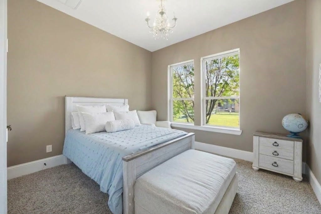 5414 Lake Hill Farm Way, Fulshear, TX 77441 Bedroom featuring warm neutral wall paint, plush wall-to-wall carpeting, high baseboards, a mini chandelier ceiling light, and double windows overlooking the yard.
