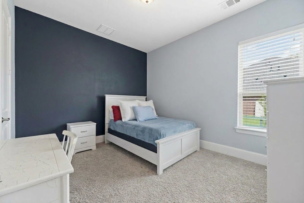 5414 Lake Hill Farm Way, Fulshear, TX 77441 Bedroom featuring a floor-to-ceiling chalkboard accent wall, light blue painted walls, carpet flooring, baseboards, and a large single window with interior blinds.