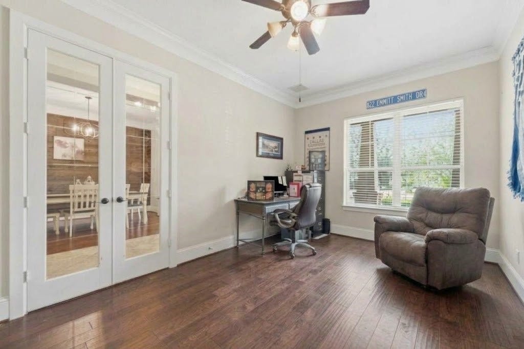 5414 Lake Hill Farm Way, Fulshear, TX 77441 Angle of the home office displaying the dark wood-look flooring, crown molding, ceiling fan, large front window, and double glass-pane French doors opening to the main foyer.