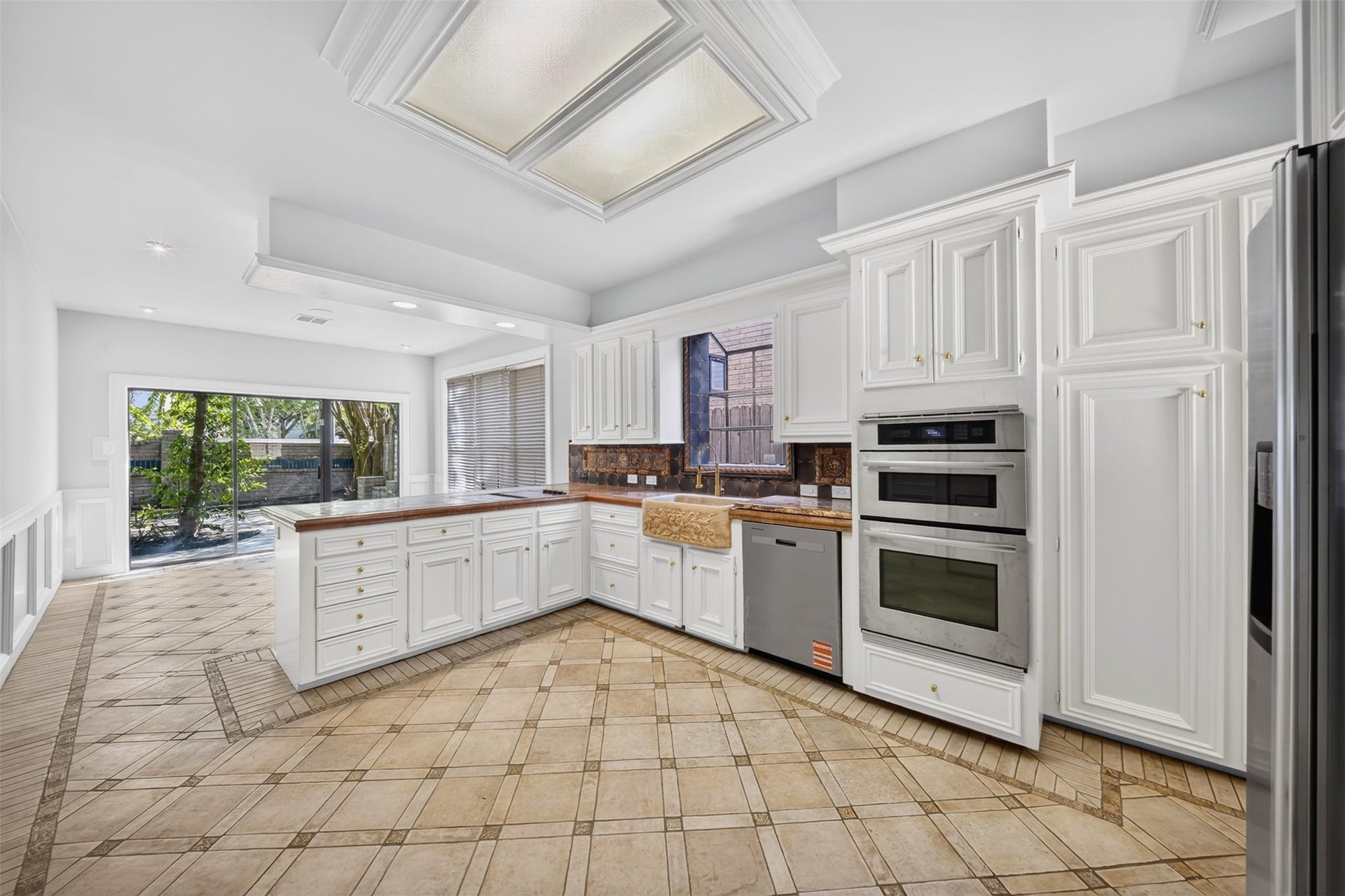 Kitchen with white cabinetry, stacked built-in appliances and an adjoining breakfast area.