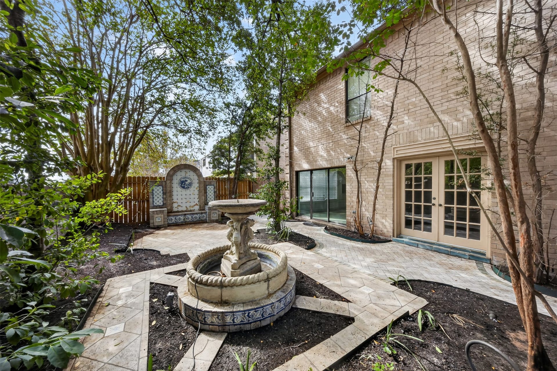Courtyard fountain and tiled wall feature near French doors into the home.