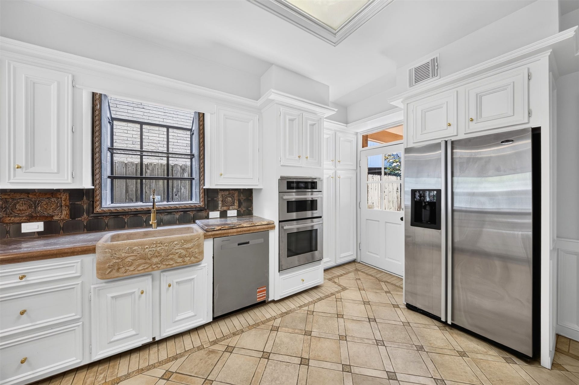 Kitchen sink beneath a window, with a decorative apron front and stainless-finish appliances.