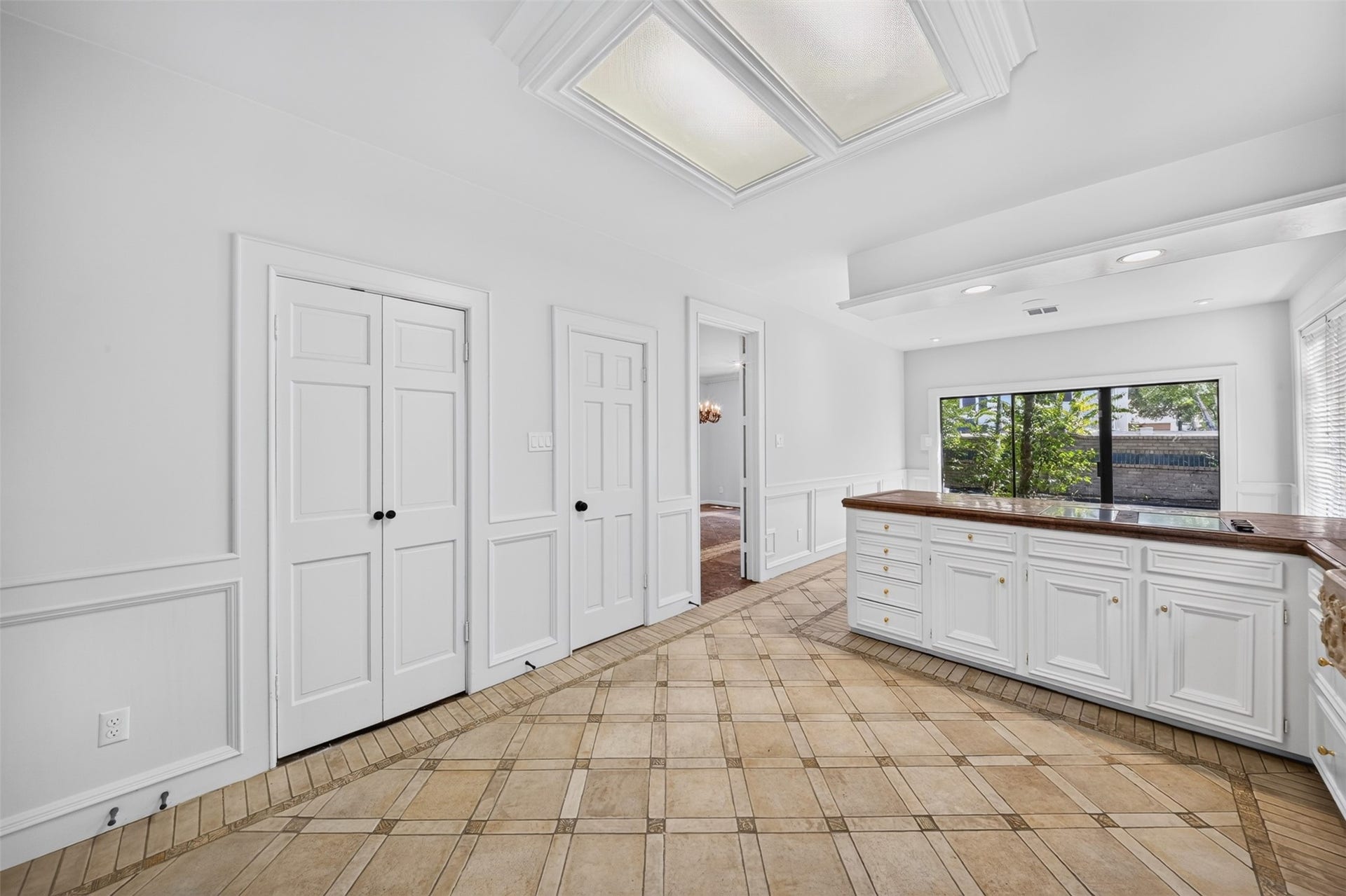 Reverse kitchen view highlights lower cabinetry, the breakfast counter and nearby doorways.