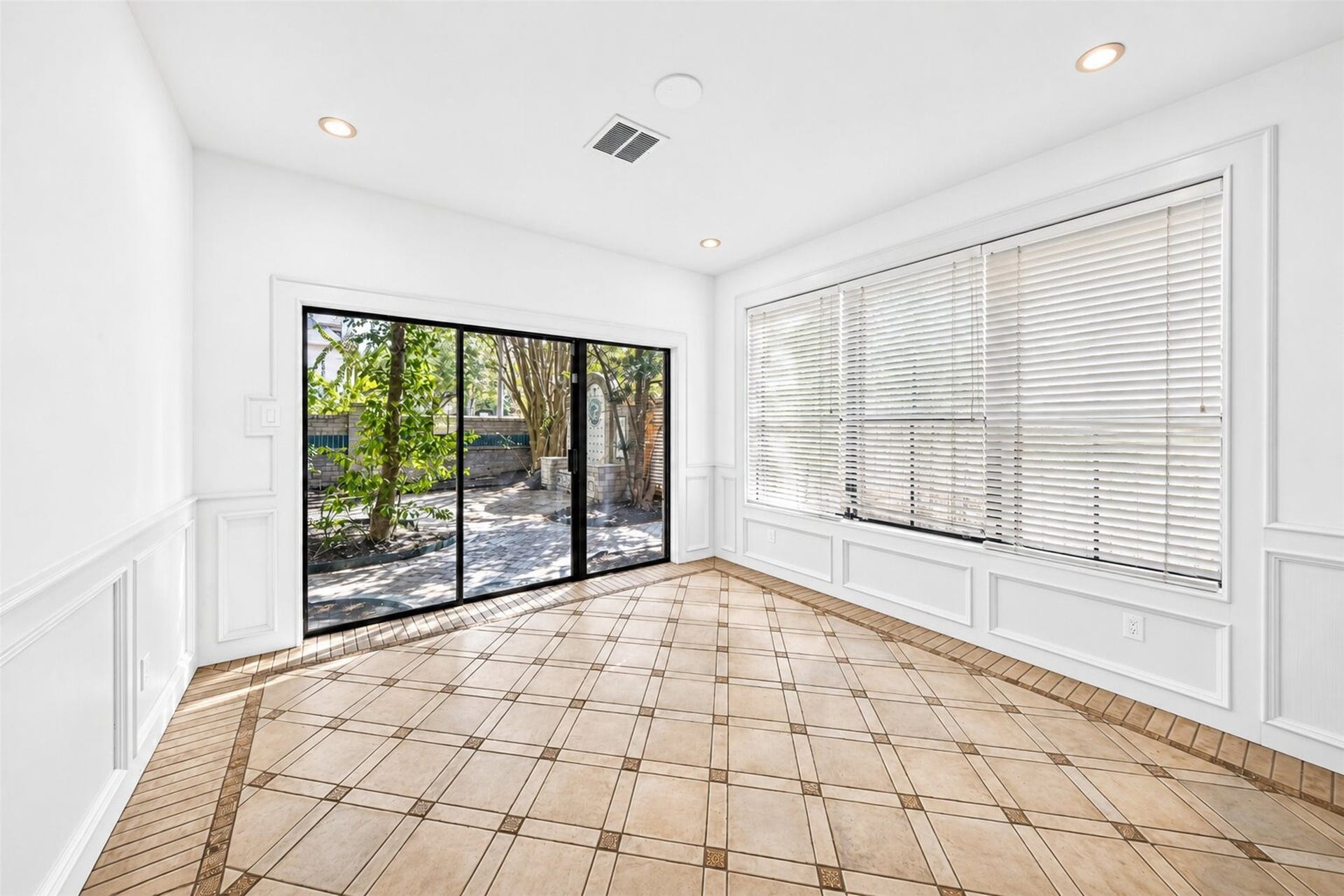 Breakfast area with wall trim, a wide window and sliding glass doors to the courtyard.