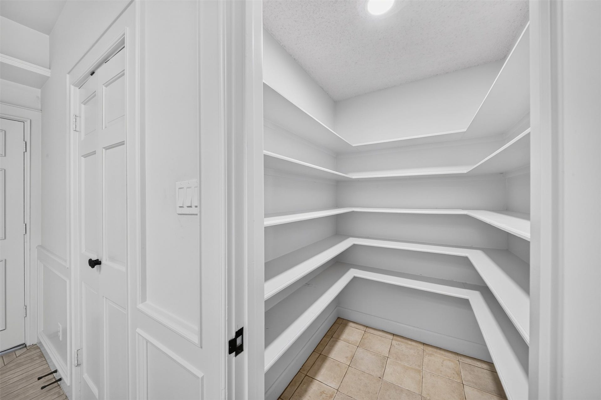 Walk-in pantry lined with wraparound open shelving.