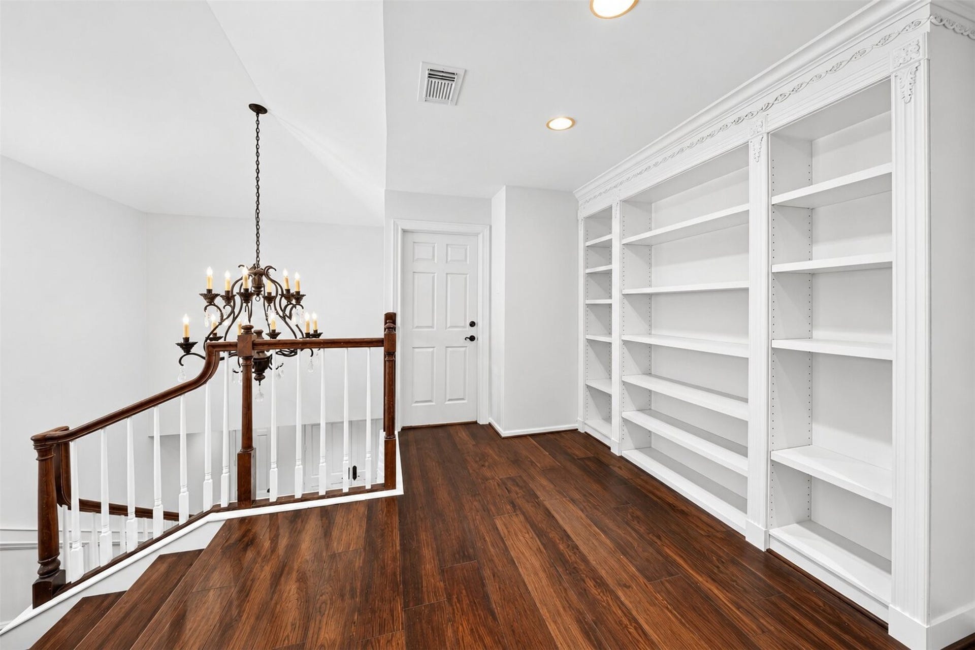 Upstairs landing with built-in bookshelves overlooking the staircase and foyer chandelier.