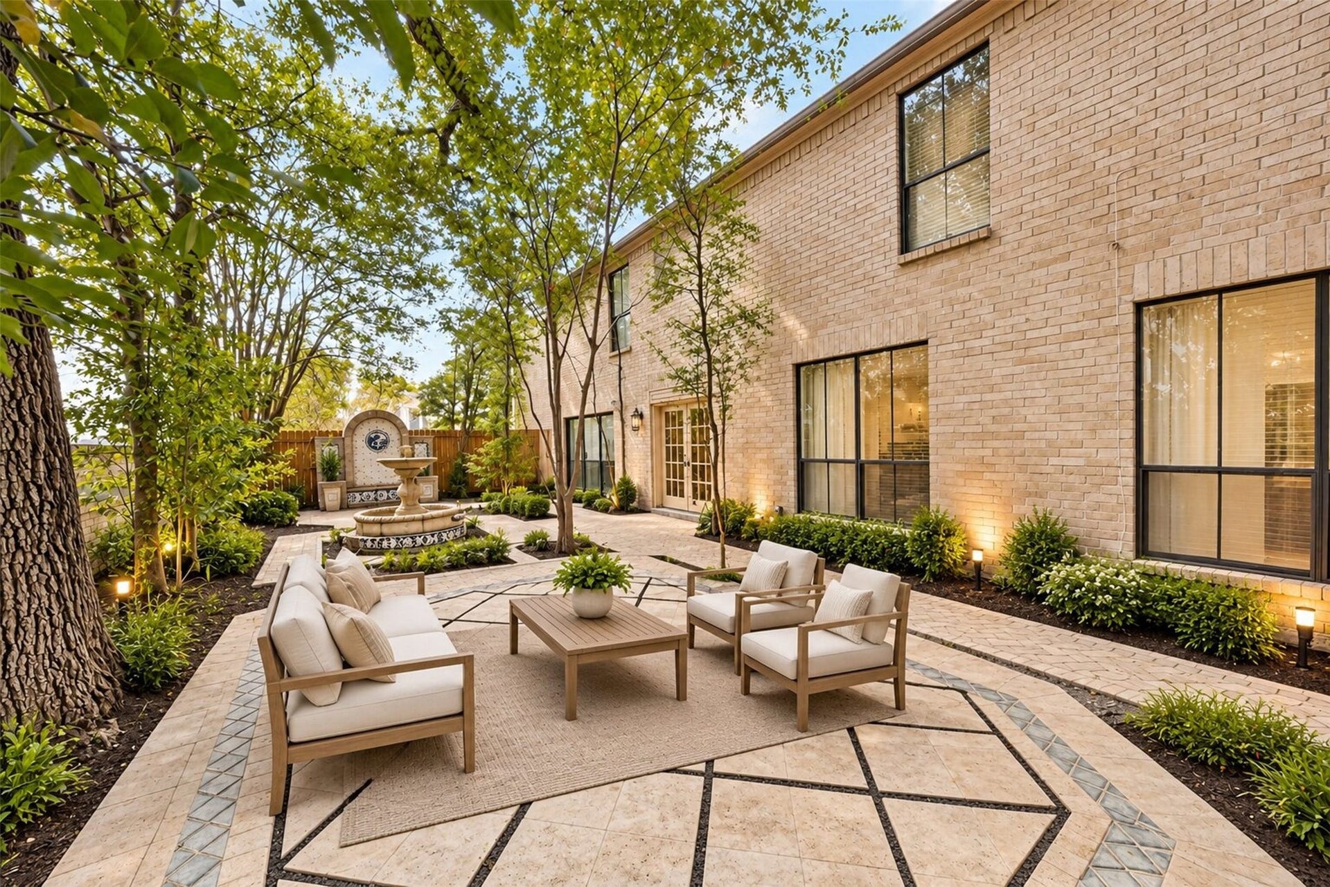 Inviting courtyard framed by mature trees, with geometric paving, a decorative fountain and French doors opening to the home. Virtually staged with digitally enhanced landscaping.