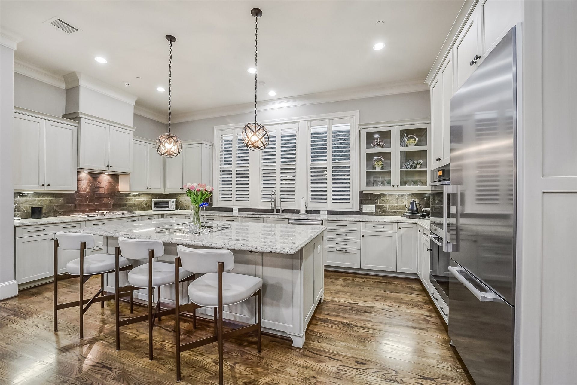 11 Southside Circle, Southside Place, TX 77025 Exceptional chef's kitchen featuring gleaming cabinetry, spacious countertops, and a large center island with a breakfast bar and elegant pendant lighting. Bright natural windows complete this sophisticated and functional design.