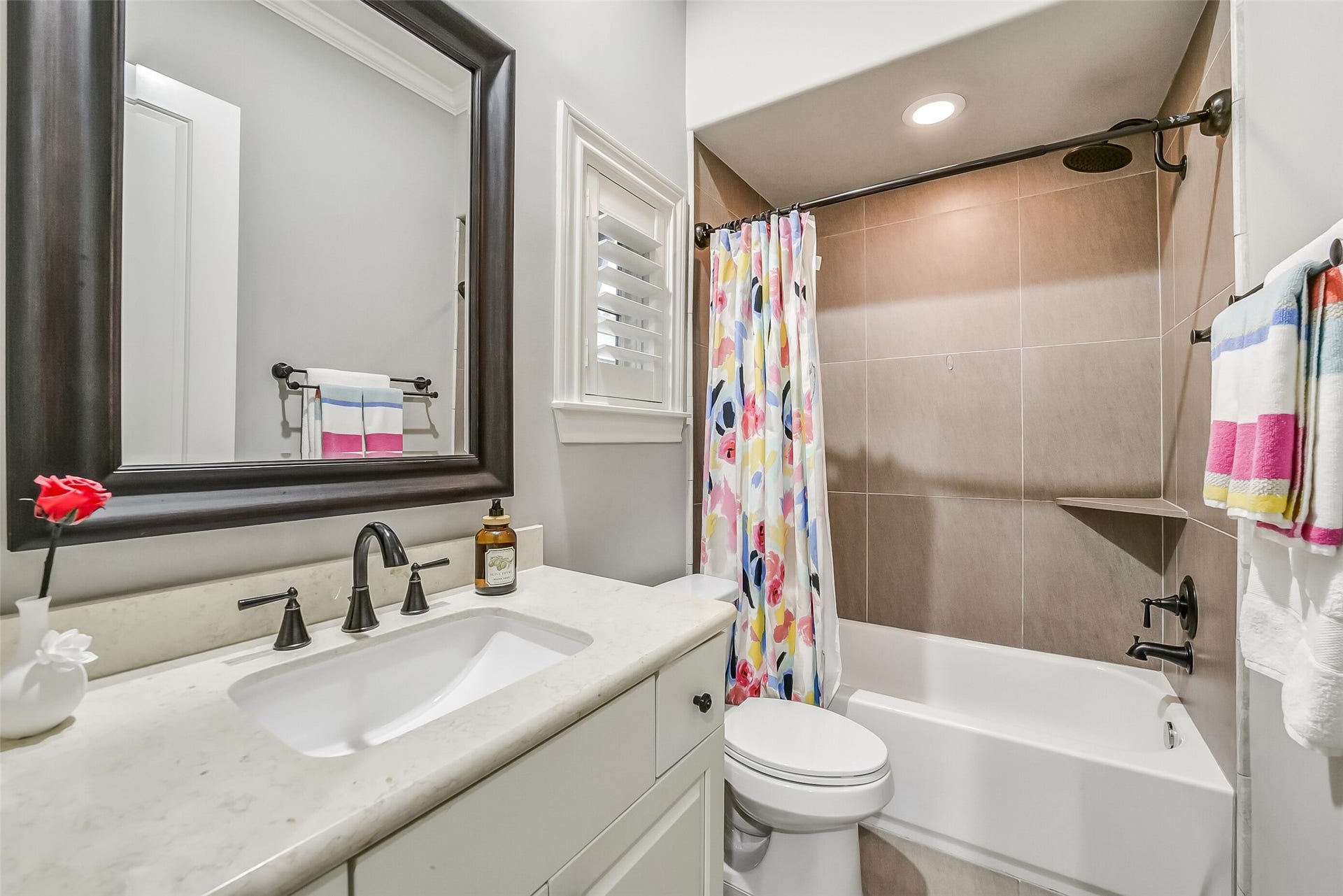 11 Southside Circle, Southside Place, TX 77025 Ensuite bath features a vanity, a charming window with plantation shutters, and a tub/shower combo complete with a built-in shelf for added convenience.