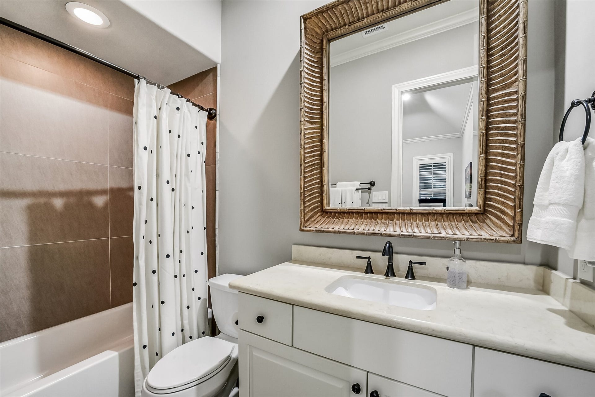 11 Southside Circle, Southside Place, TX 77025 Private ensuite bath offers comfort and style for a secondary bedroom, featuring a vanity with beautifully framed mirror and tub/shower combo.