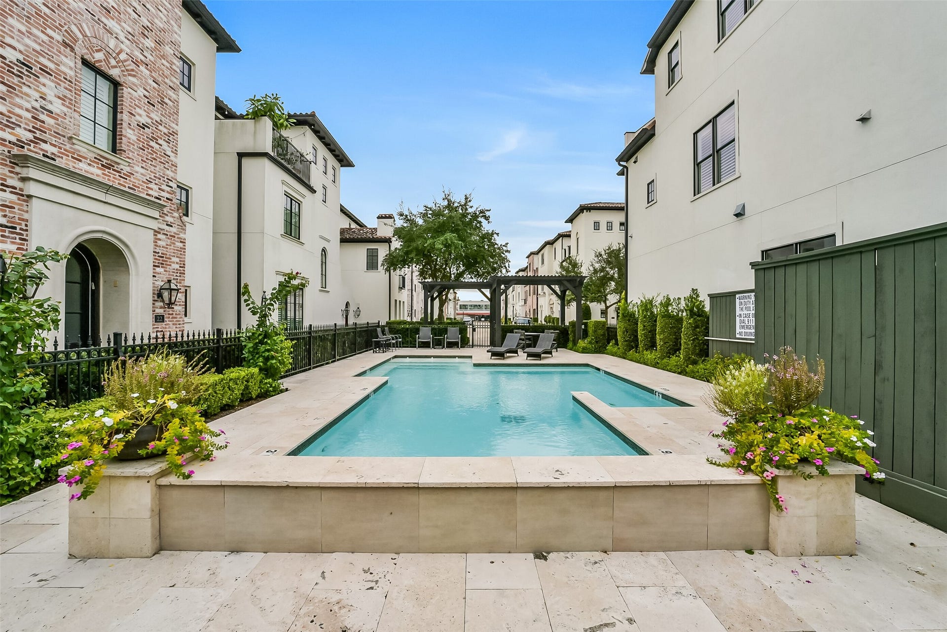 11 Southside Circle, Southside Place, TX 77025 Resort-style community pool tucked inside the neighborhood, surrounded by travertine decking, lounge seating, and a shaded pergola. Wrought-iron fencing, lush landscaping, and colorful planters create a private, inviting retreat just steps from home.