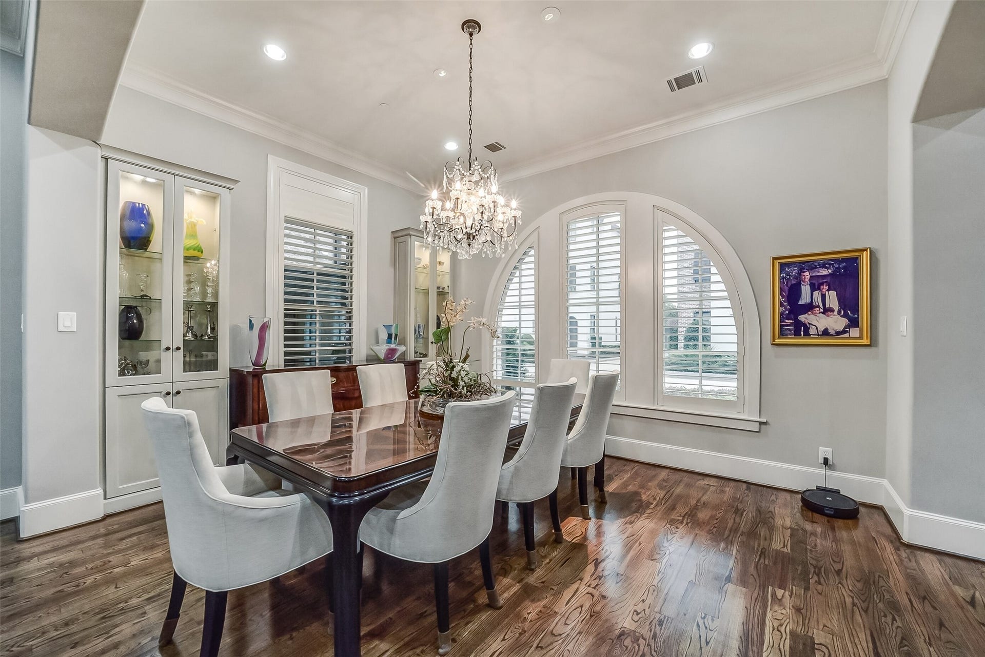 11 Southside Circle, Southside Place, TX 77025 Elegantly appointed formal dining room showcasing custom shutters, a striking arched window, and lighted, built-in glass-front display cabinets. (Note: Dining room chandelier is reserved.)
