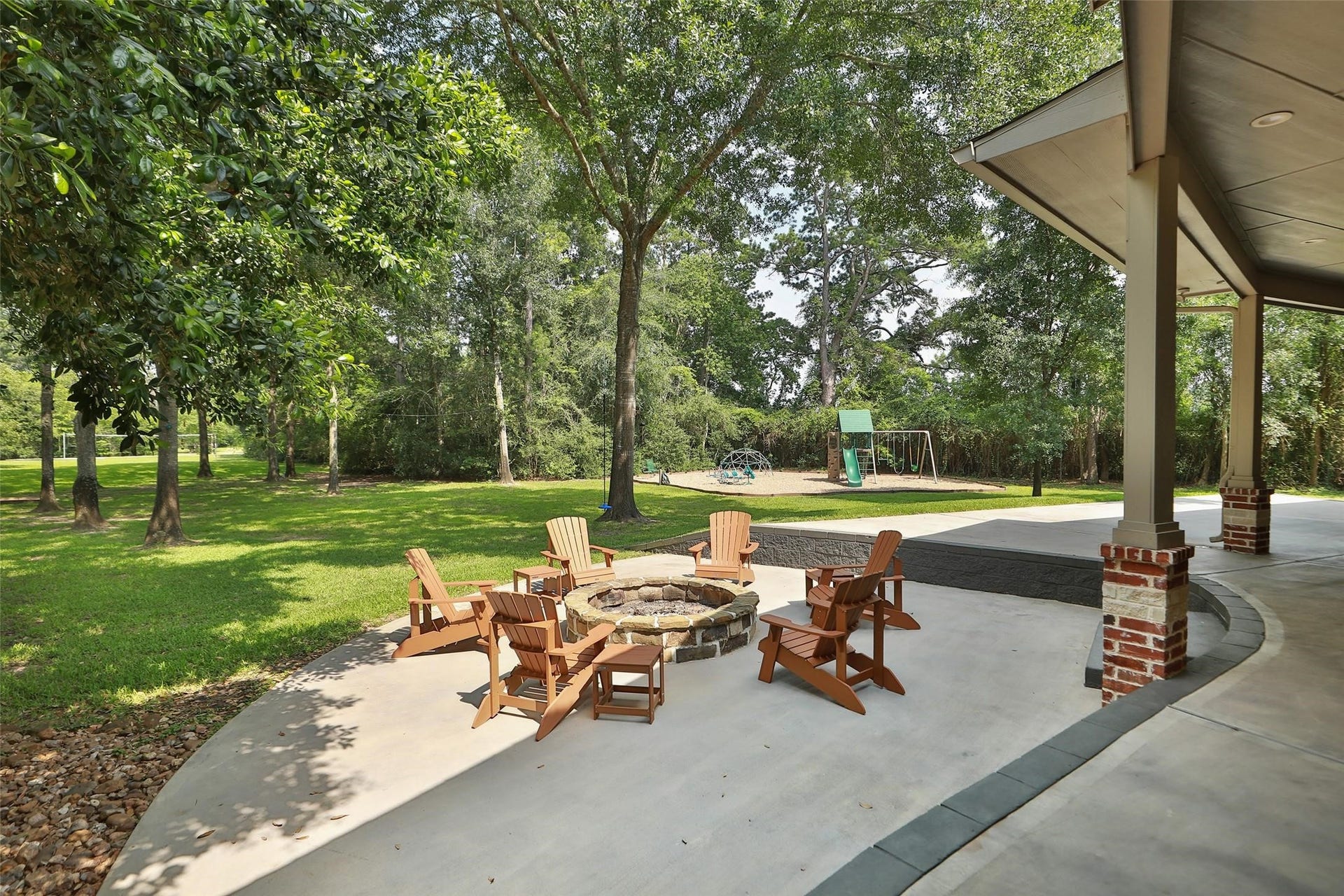 Plenty of room for a pool in the backyard. A custom stone fire pit invites cozy evenings outdoors, while the nearby playground offers endless fun for kids. Surrounded by mature trees and wide-open green space, this backyard is designed for gathering, entertaining, and creating unforgettable memories.