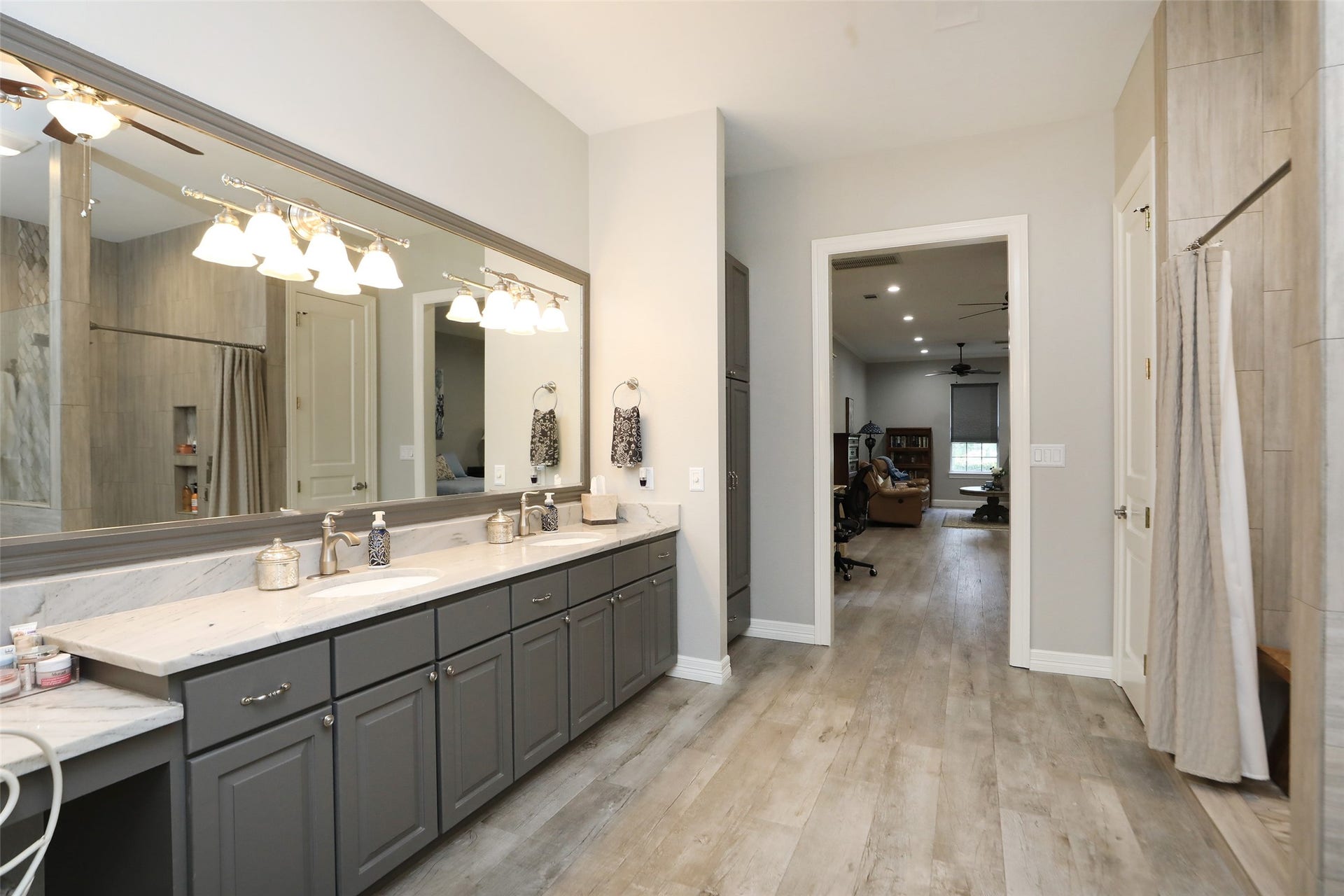 Primary bathroom with two sinks, vanity, tub and separate shower. Quartzite counters wood like tile floors.
