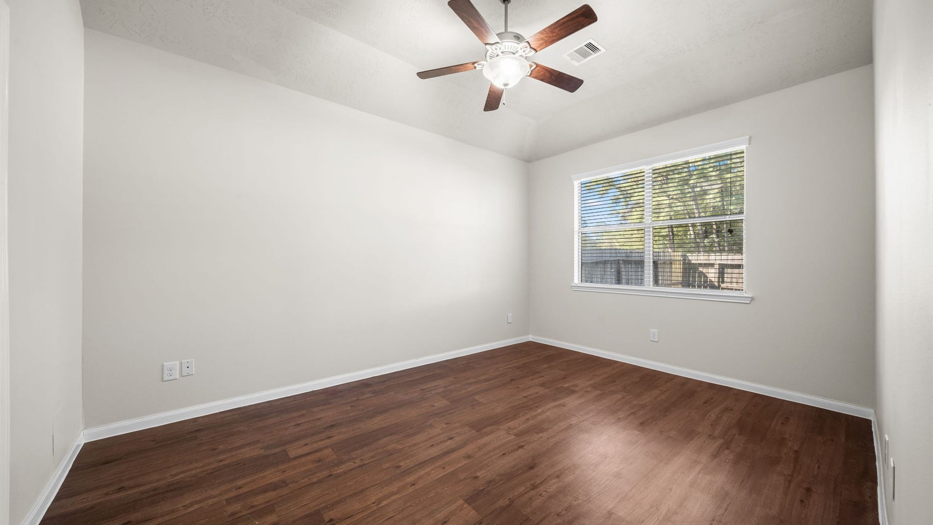 11246 Glenforest Drive, Montgomery, TX 77356 Relax and unwind in this primary bedroom featuring wood-look flooring, a ceiling fan, neutral finishes, and a large window overlooking the yard.
