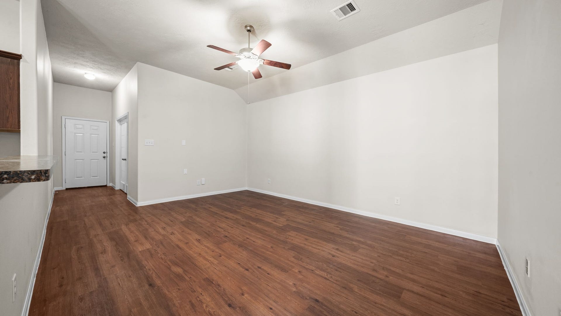 11246 Glenforest Drive, Montgomery, TX 77356 Spacious living area with vaulted ceilings, a ceiling fan, and attractive wood-look flooring, offering plenty of flexibility for your furniture and personal style.