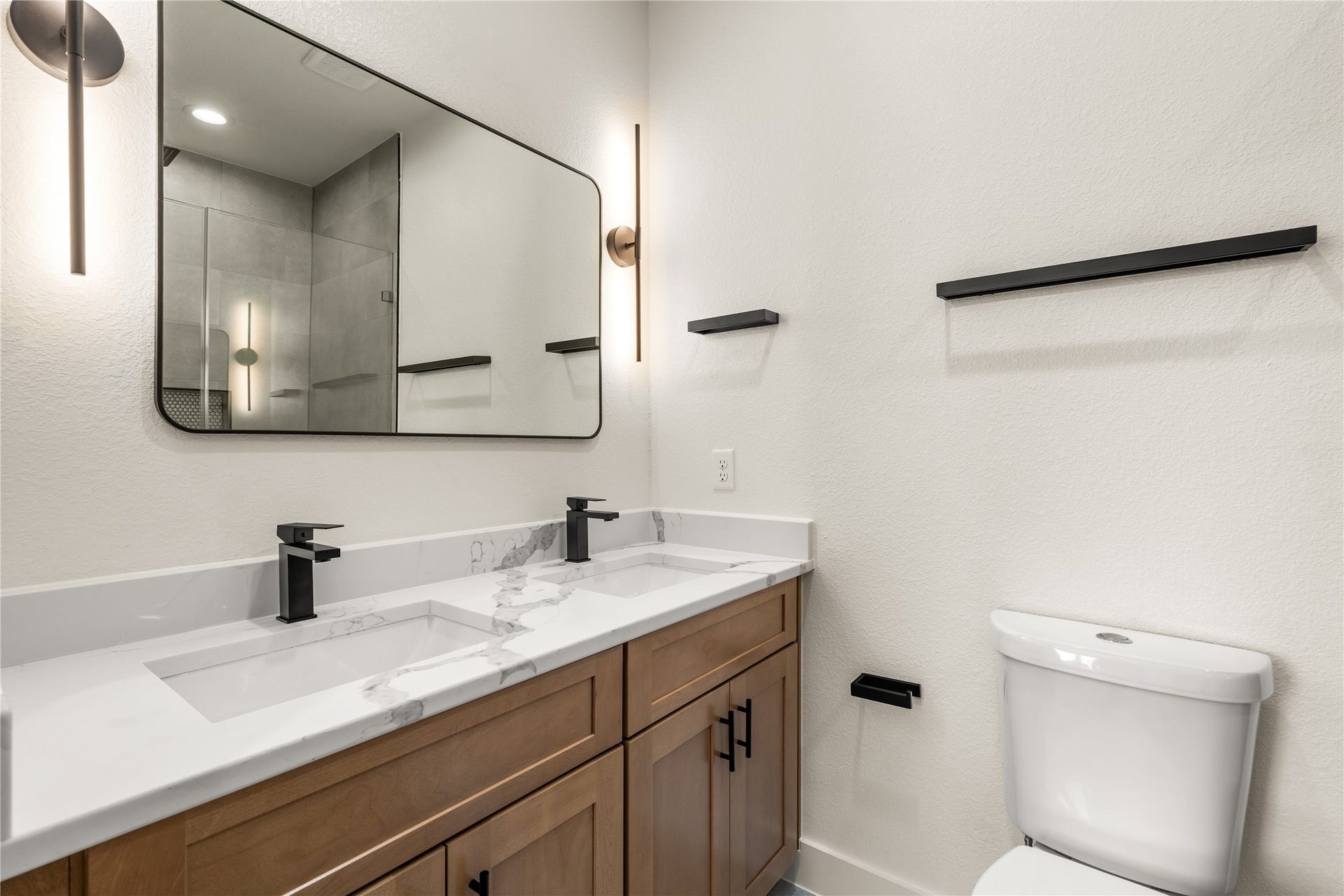 5321 Rue Street, Houston, TX 77033 Primary ensuite bath quartz dual vanity, warm wood cabinetry, sleek matte black hardware, and designer sconce lighting.