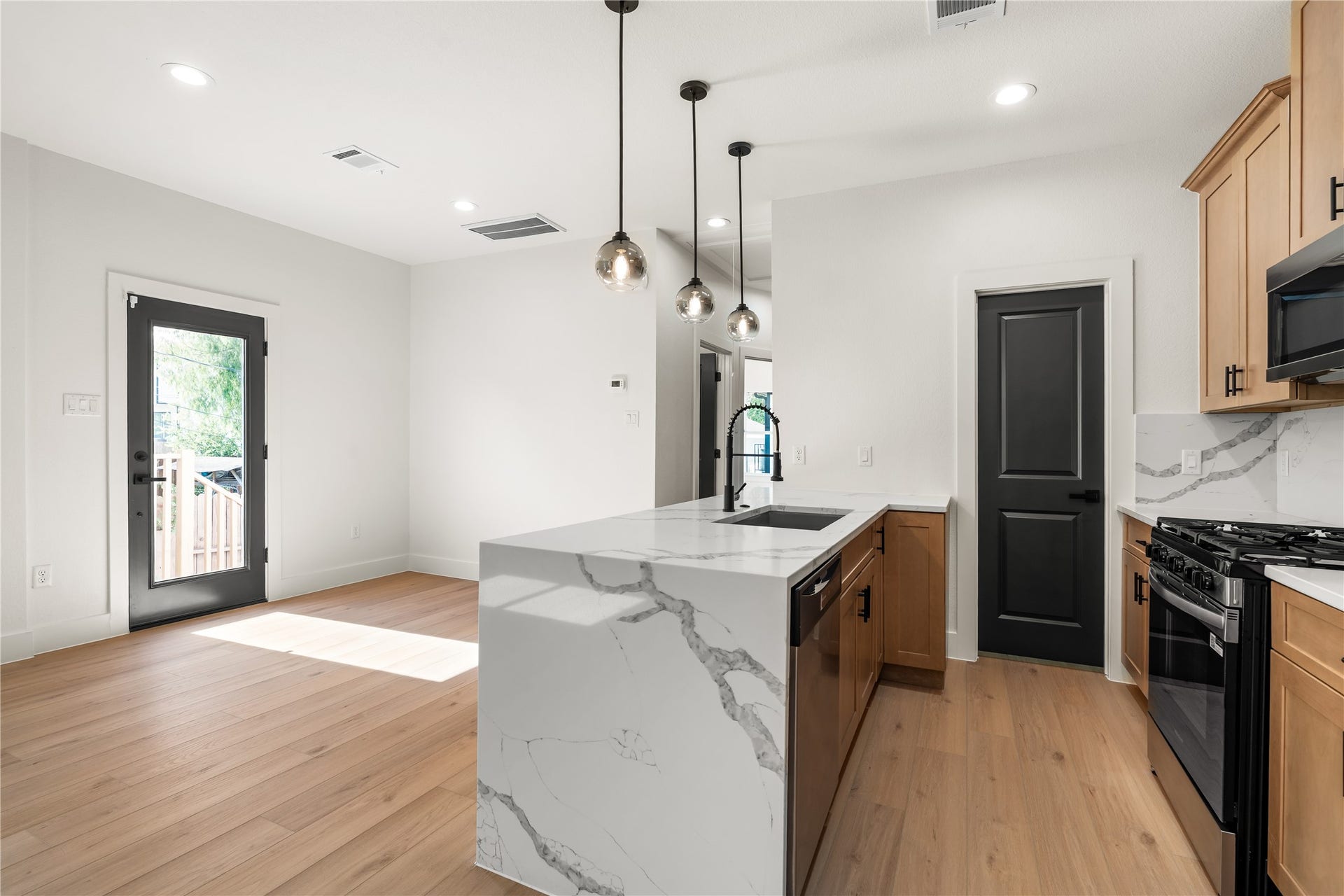 5321 Rue Street, Houston, TX 77033 Sun-drenched kitchen and dining area direct patio door connection, prep sink inset on the island, and professional gas range setup.