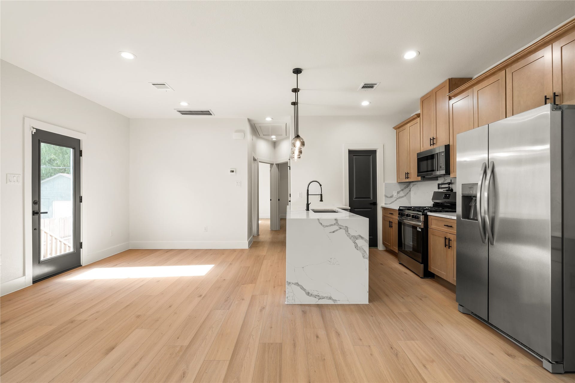 5321 Rue Street, Houston, TX 77033 Gourmet kitchen setup statement waterfall island with undermount sink, pot filler over gas range, stainless steel appliances, and custom warm wood cabinetry.