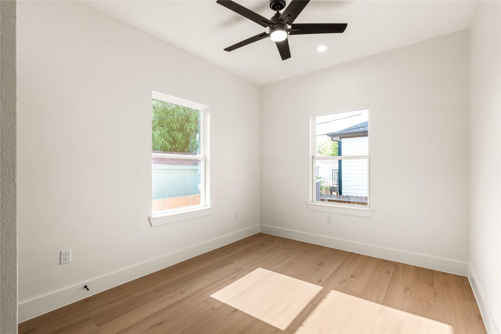 5321 Rue Street, Houston, TX 77033 Bright secondary bedroom dual vinyl windows capturing morning light, clean baseboards, and wide-plank flooring.