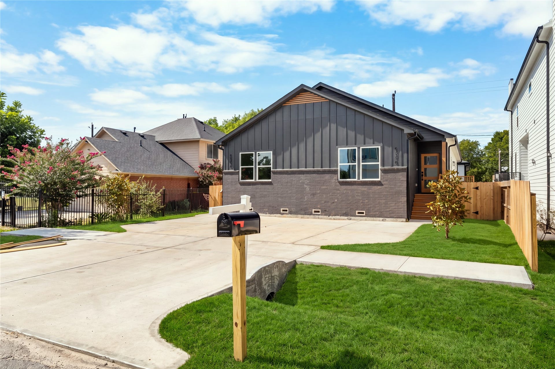 5321 Rue Street, Houston, TX 77033 Striking curb appeal anchored by clean architectural lines warm cedar accents, sleek black mailbox post, and crisp surrounding green lawn.