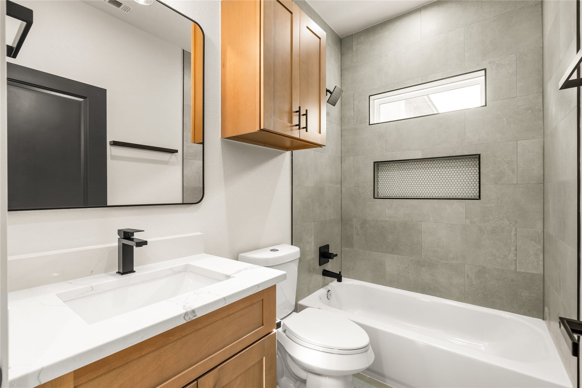 5321 Rue Street, Houston, TX 77033 Full secondary bathroom designer tile surround extending to the ceiling, tub/shower combo with mosaic niche, and custom wood vanity.