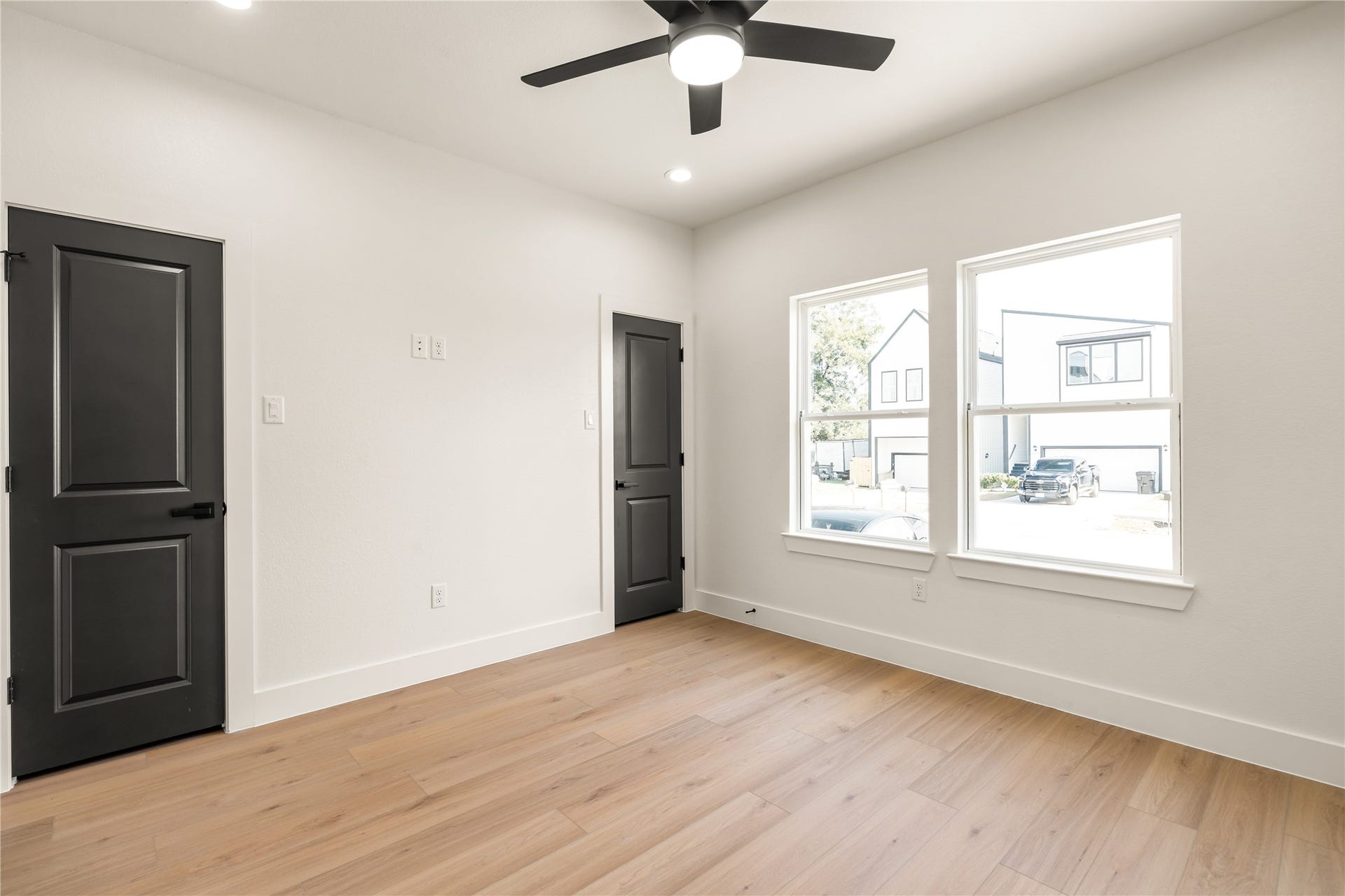 5321 Rue Street, Houston, TX 77033 Primary suite sanctuary oversized windows streaming natural light, warm oak-look flooring, and double closet doors.