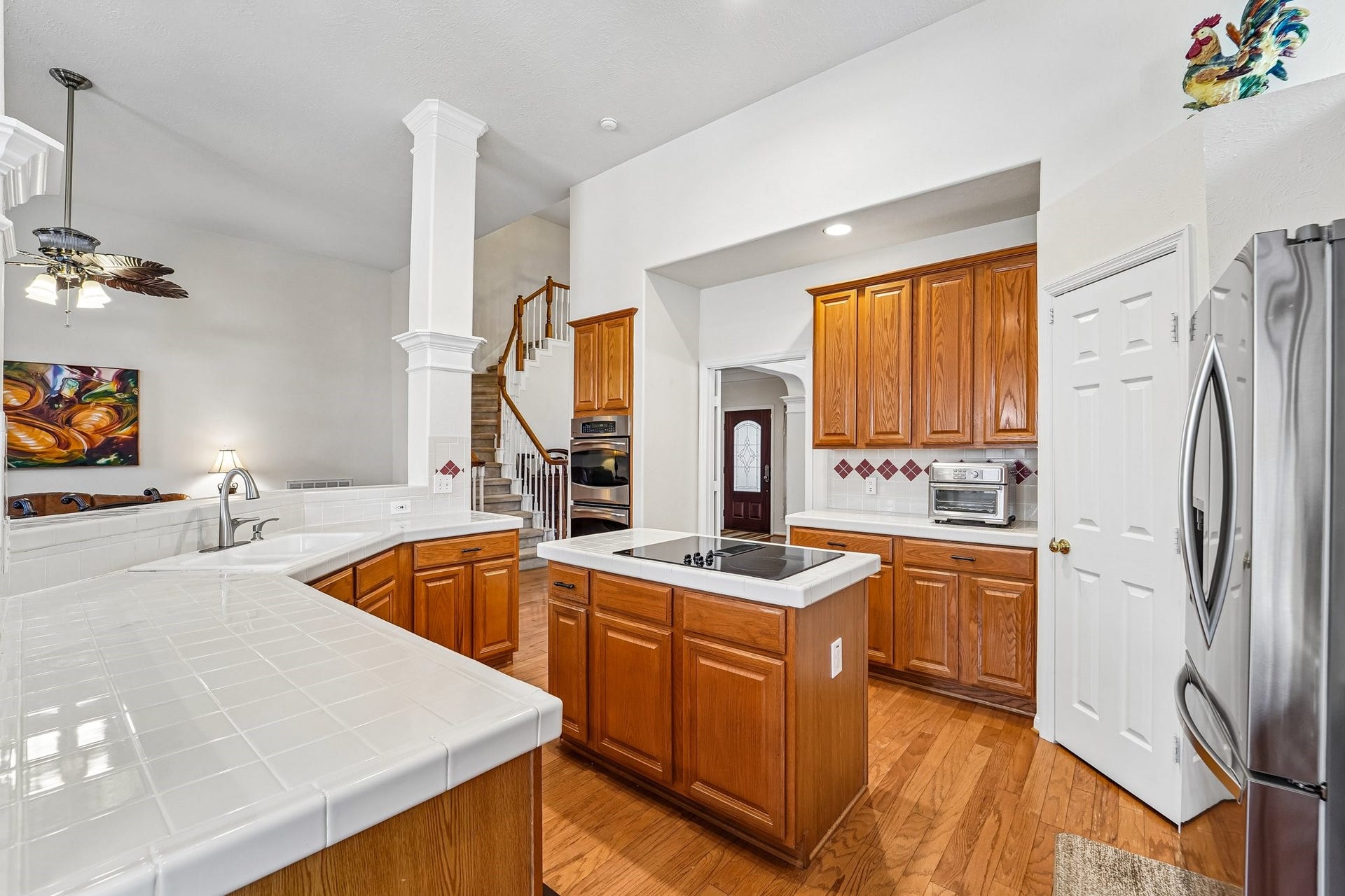 14 Serene Creek Place, The Woodlands, TX 77382 Spacious kitchen featuring warm wood cabinetry, sleek stainless steel appliances, and an inviting central island with a cooktop, perfect for culinary enthusiasts.