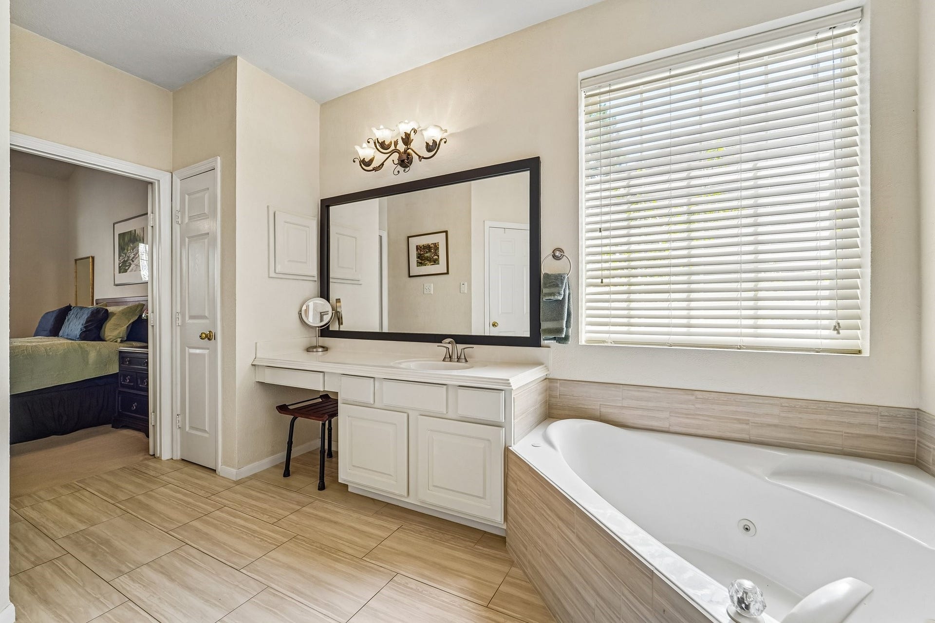 14 Serene Creek Place, The Woodlands, TX 77382 Primary bathroom features a luxurious corner bathtub, dual vanities with elegant lighting, and a large mirror, complemented by a separate glass-enclosed shower.