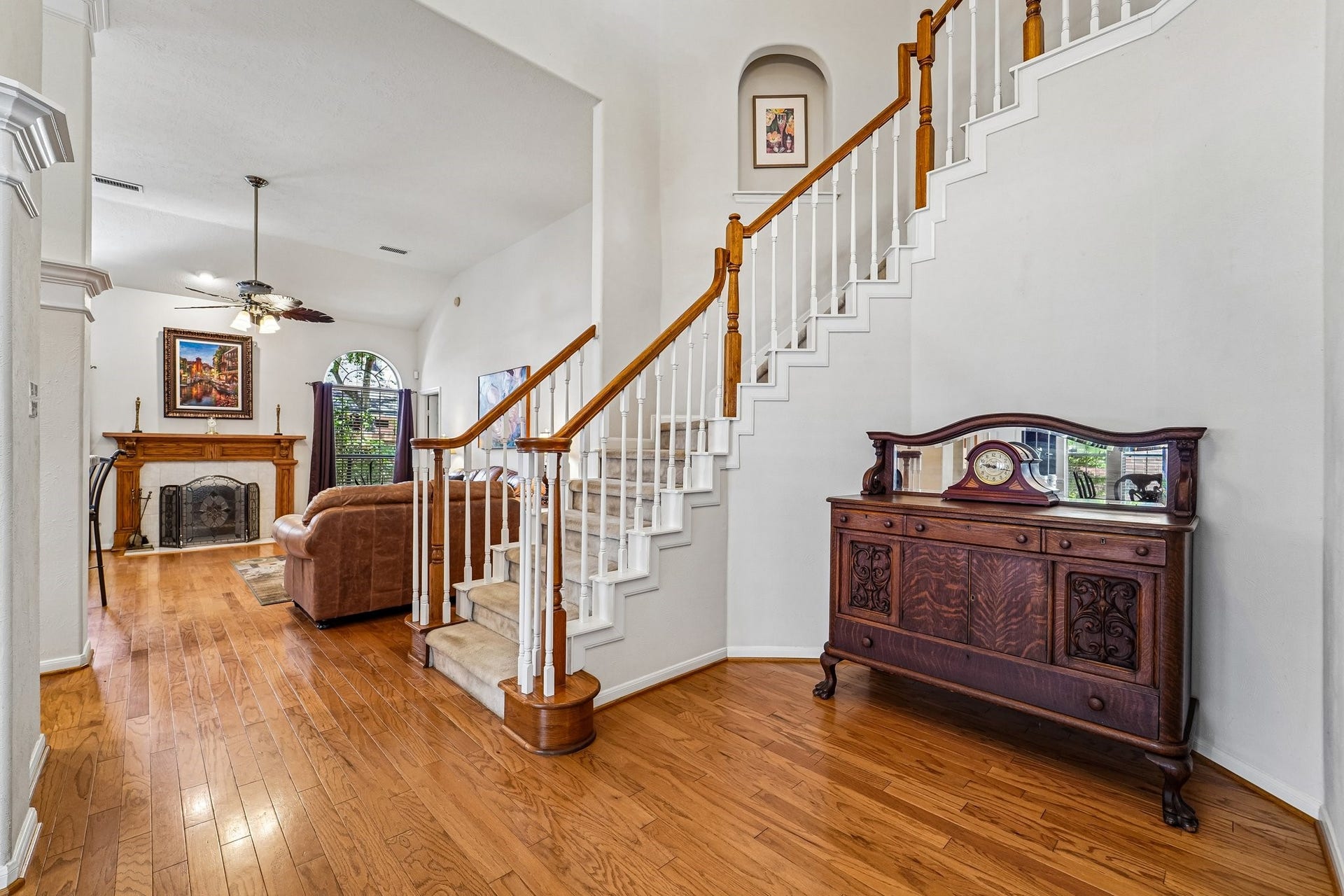 14 Serene Creek Place, The Woodlands, TX 77382 View from the foyer features a grand staircase, hardwood floors, and a cozy fireplace, creating a warm and inviting atmosphere.