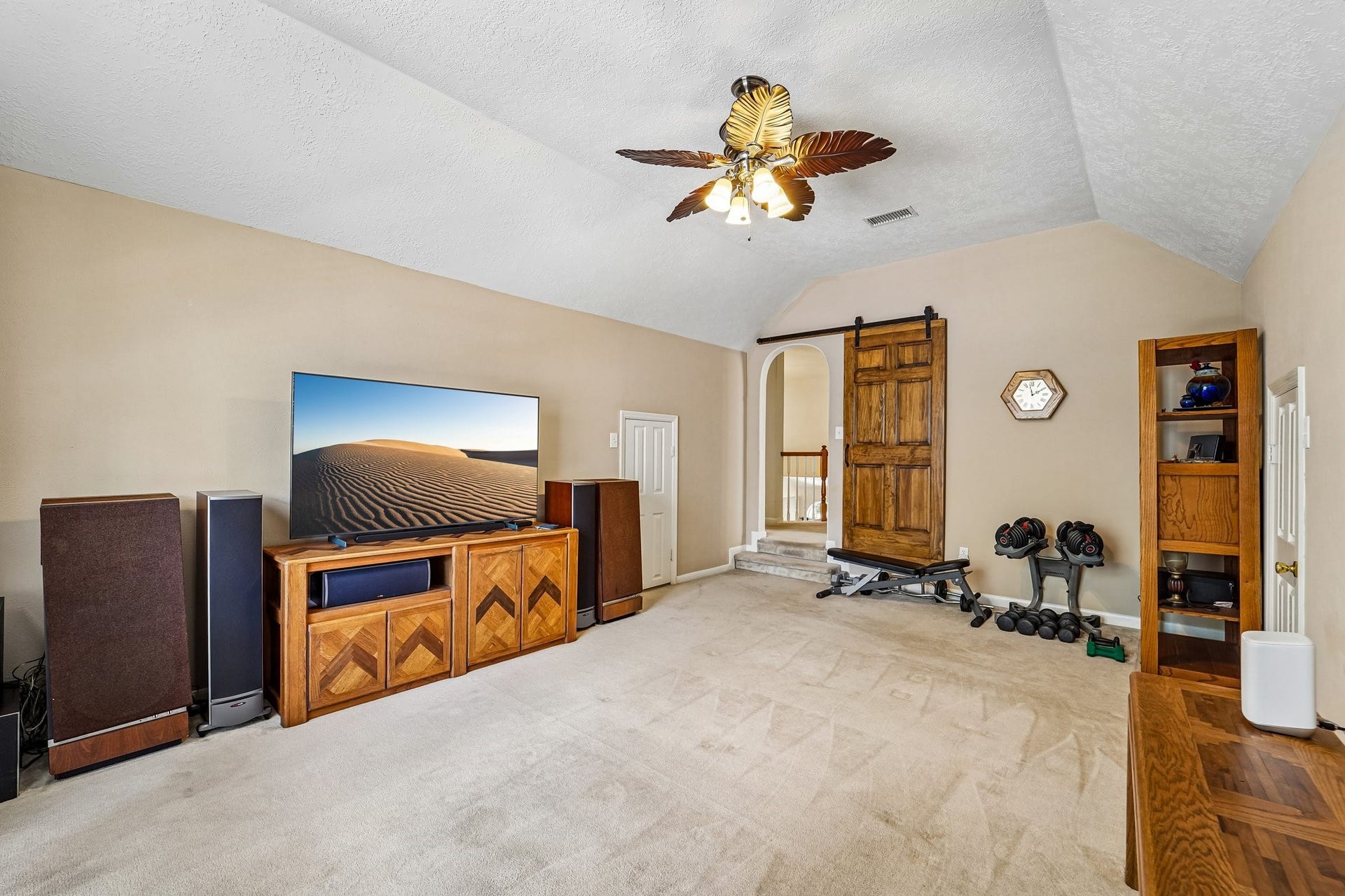 14 Serene Creek Place, The Woodlands, TX 77382 Spacious entertainment room featuring built-in bookshelves, a large window with an arched design, and ample space for seating and media equipment.