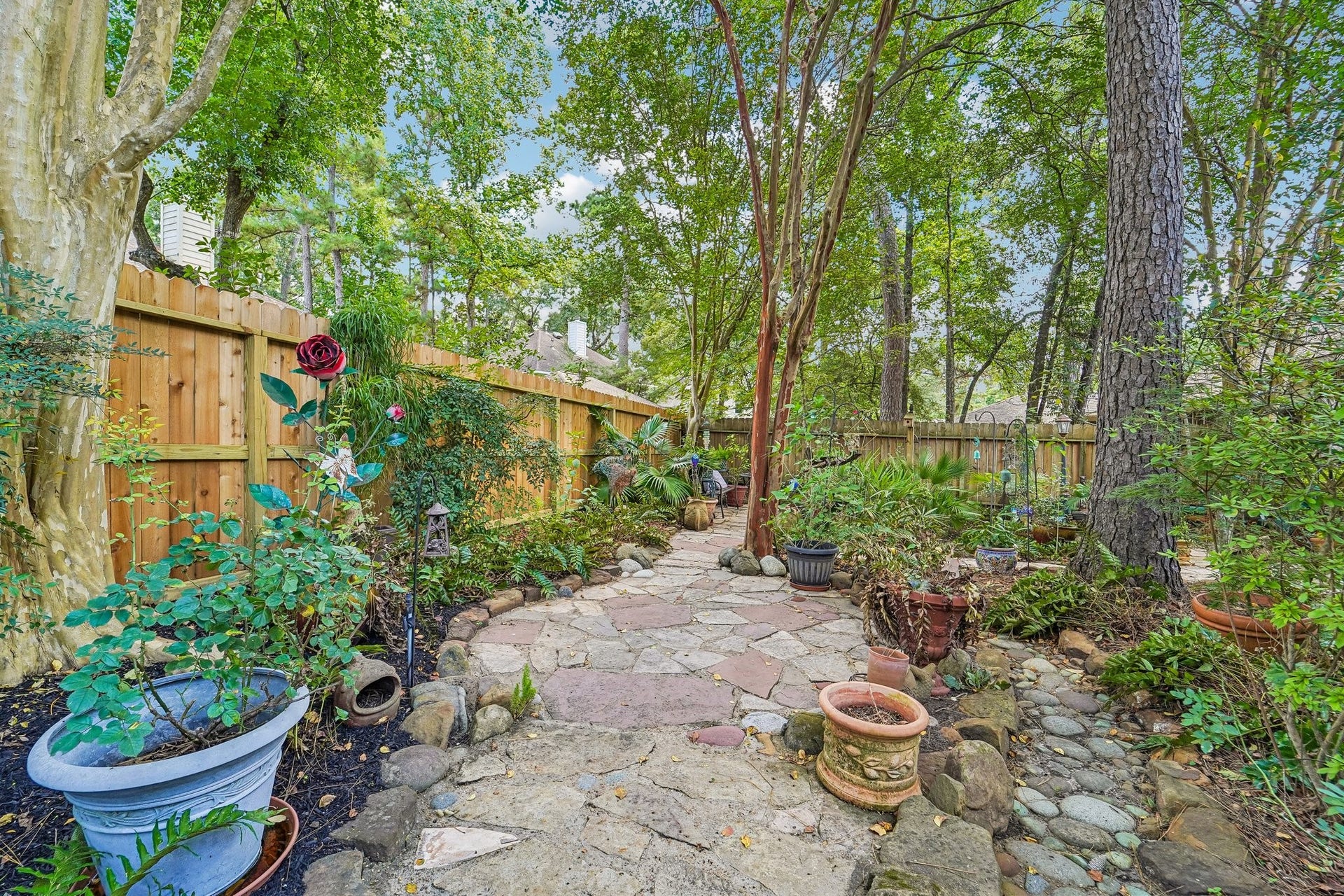 14 Serene Creek Place, The Woodlands, TX 77382 Charming garden oasis with a stone pathway, lush greenery, and mature trees, perfect for relaxation and outdoor enjoyment.