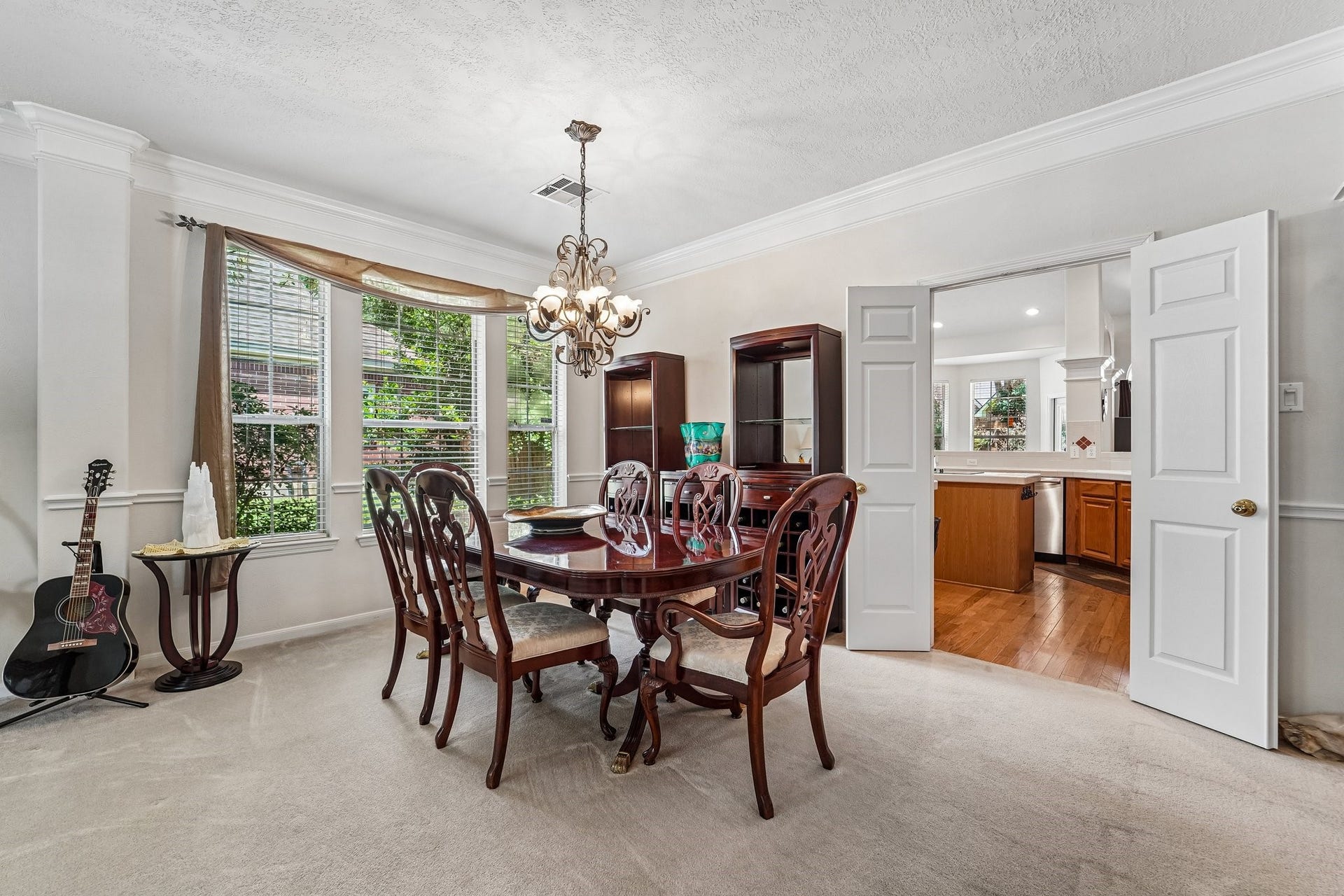 14 Serene Creek Place, The Woodlands, TX 77382 Formal dining room with large windows for natural light, and warm wood furnishings, seamlessly connected to the kitchen through French doors.